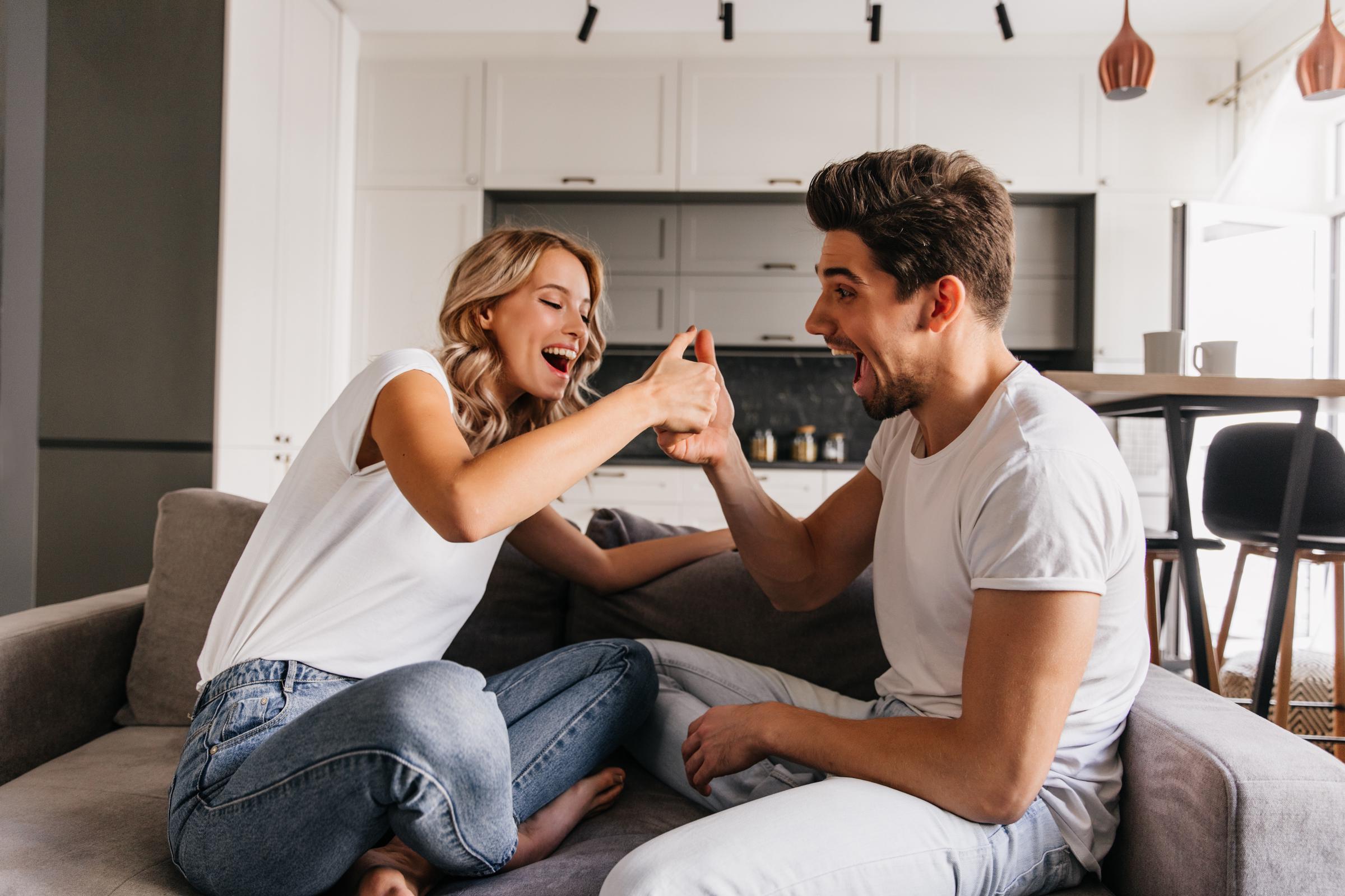 Un couple assis sur le canapé et riant | Source : Freepik