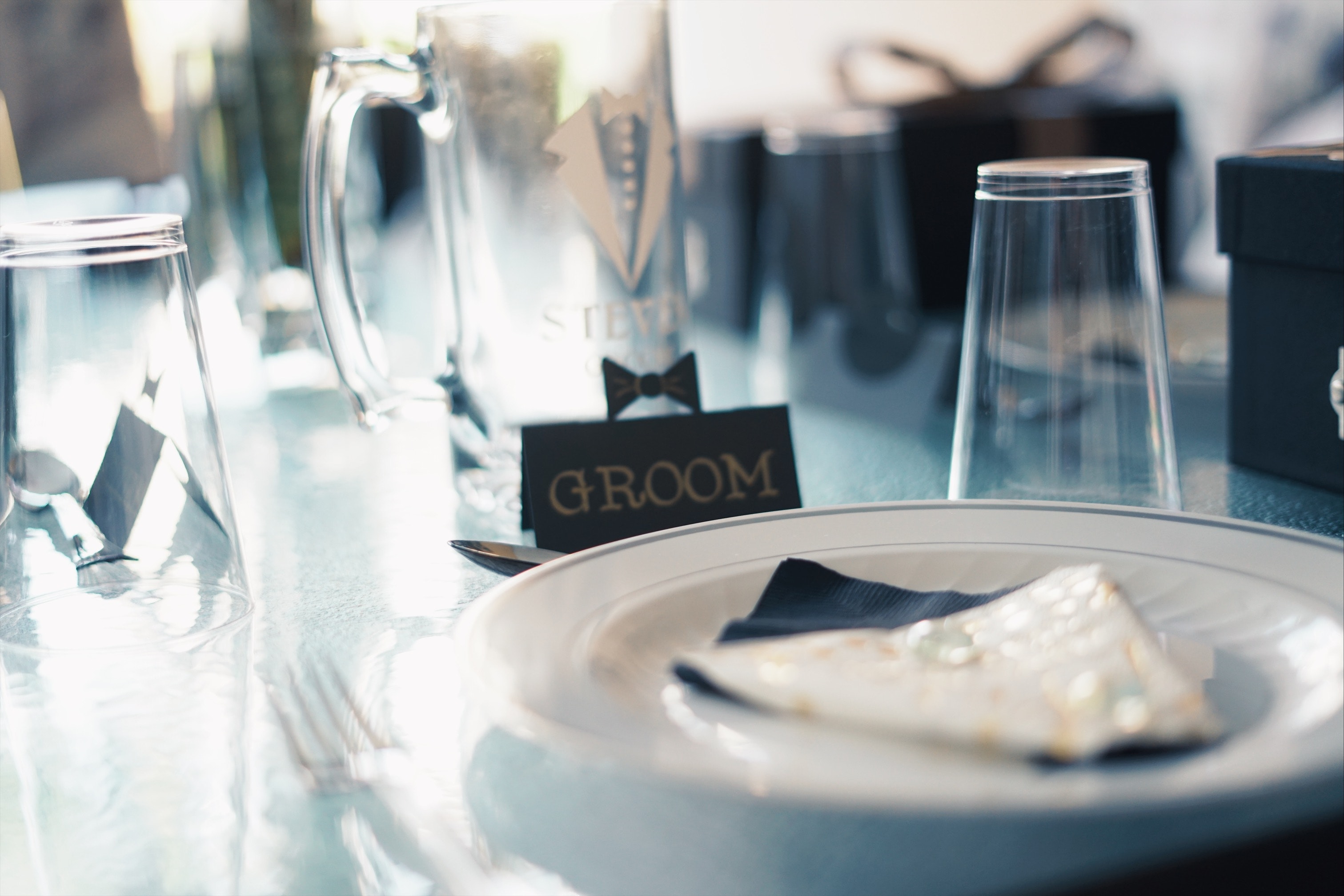 Assiette ronde en céramique blanche près de tasses en verre et d'un panneau de marié | Source : Pexels