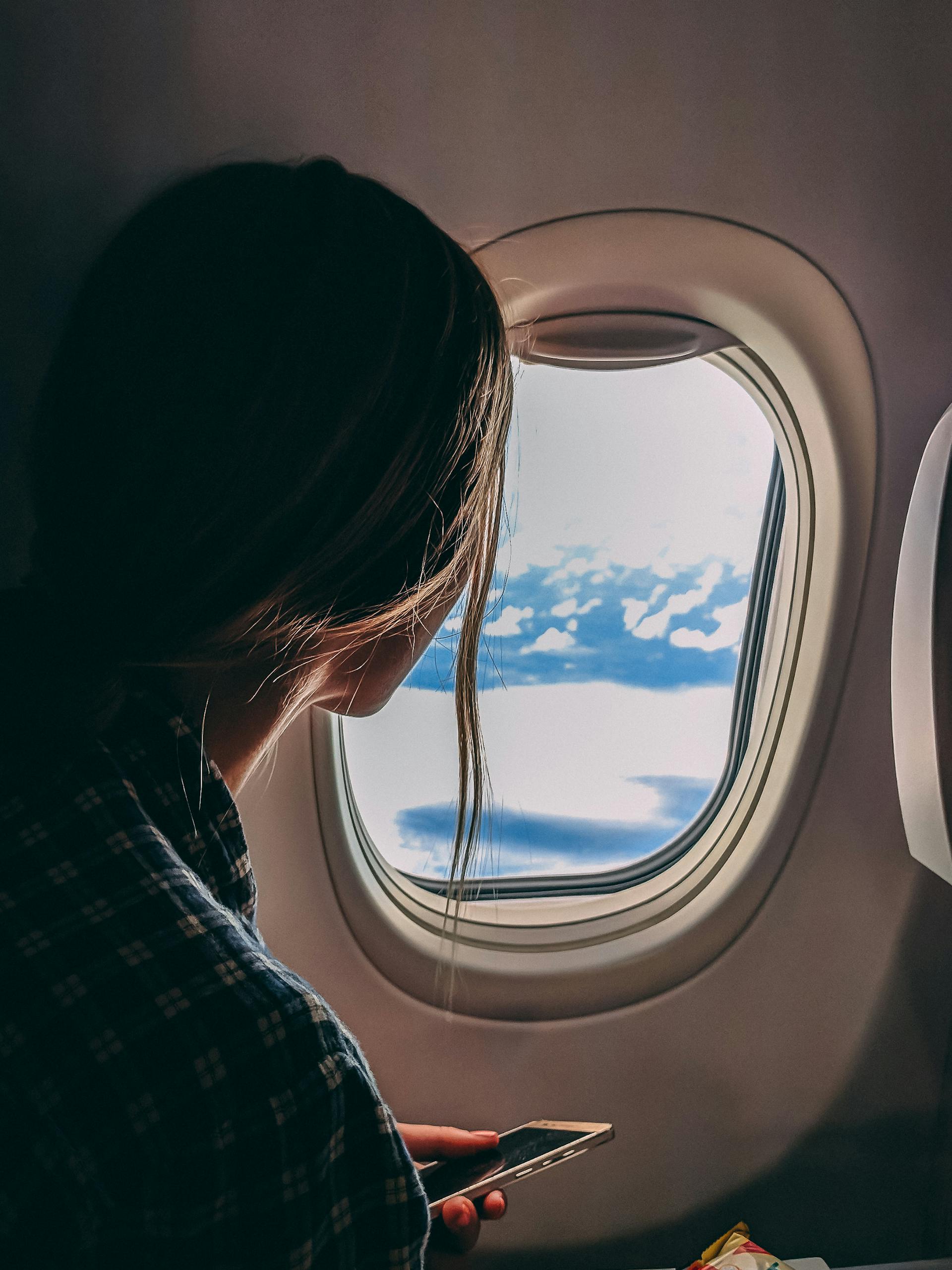 Une femme tenant son smartphone alors qu'elle se trouve dans un avion | Source : Pexels