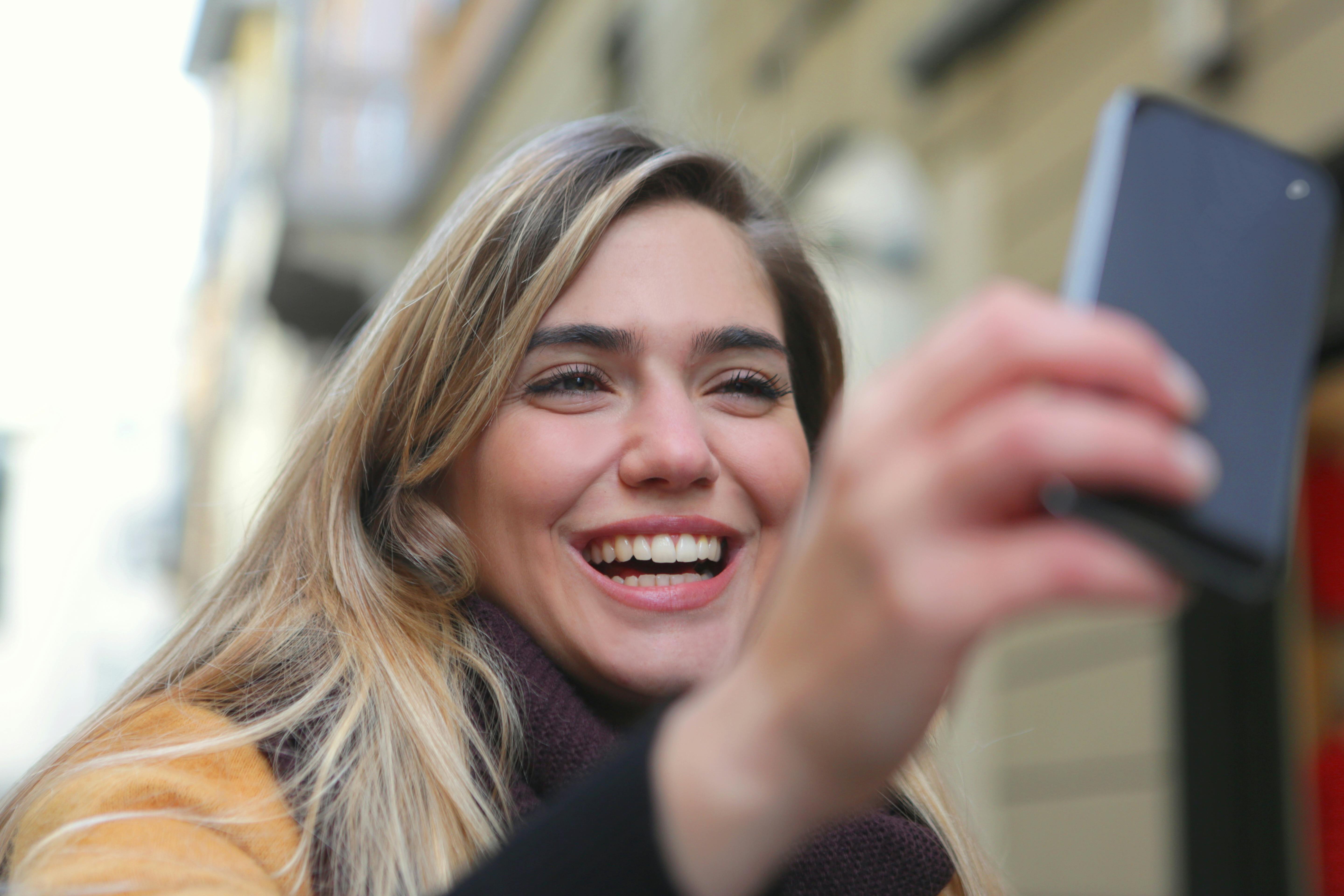 Une femme qui rit en regardant son téléphone | Source : Pexels