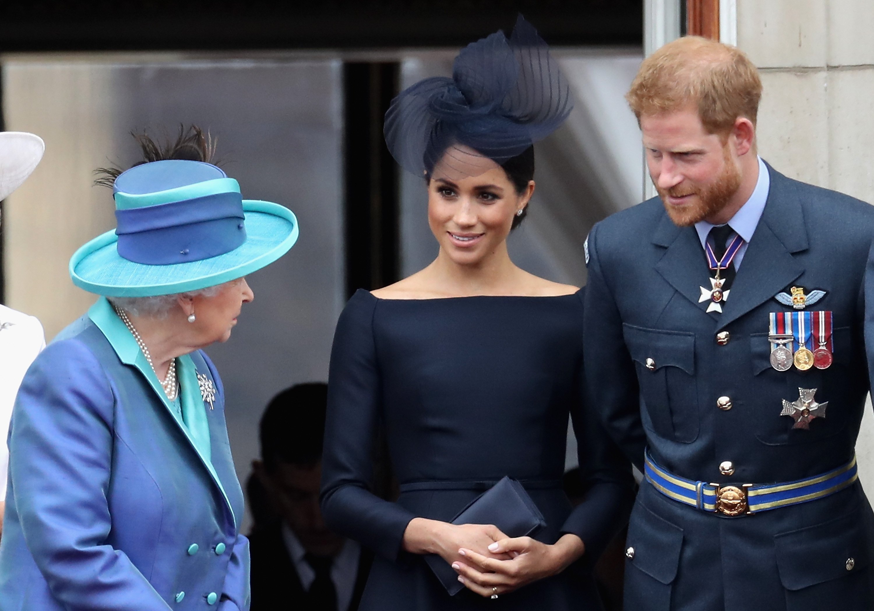 La reine Elizabeth II, Meghan Markle et le prince Harry photographiés en train de regarder le défilé aérien de la RAF sur le balcon du palais de Buckingham, le 10 juillet 2018 à Londres, en Angleterre. │ Source : Getty Images