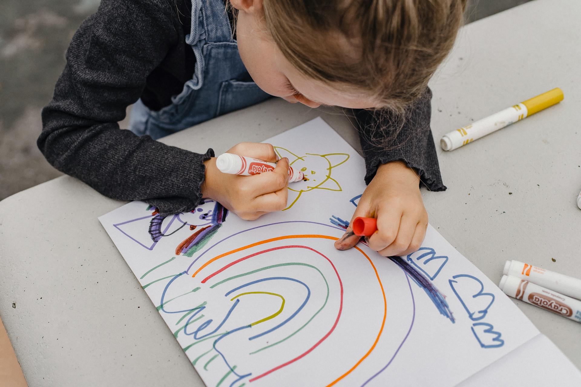 Gros plan sur une petite fille qui dessine avec des marqueurs sur un papier | Source : Pexels