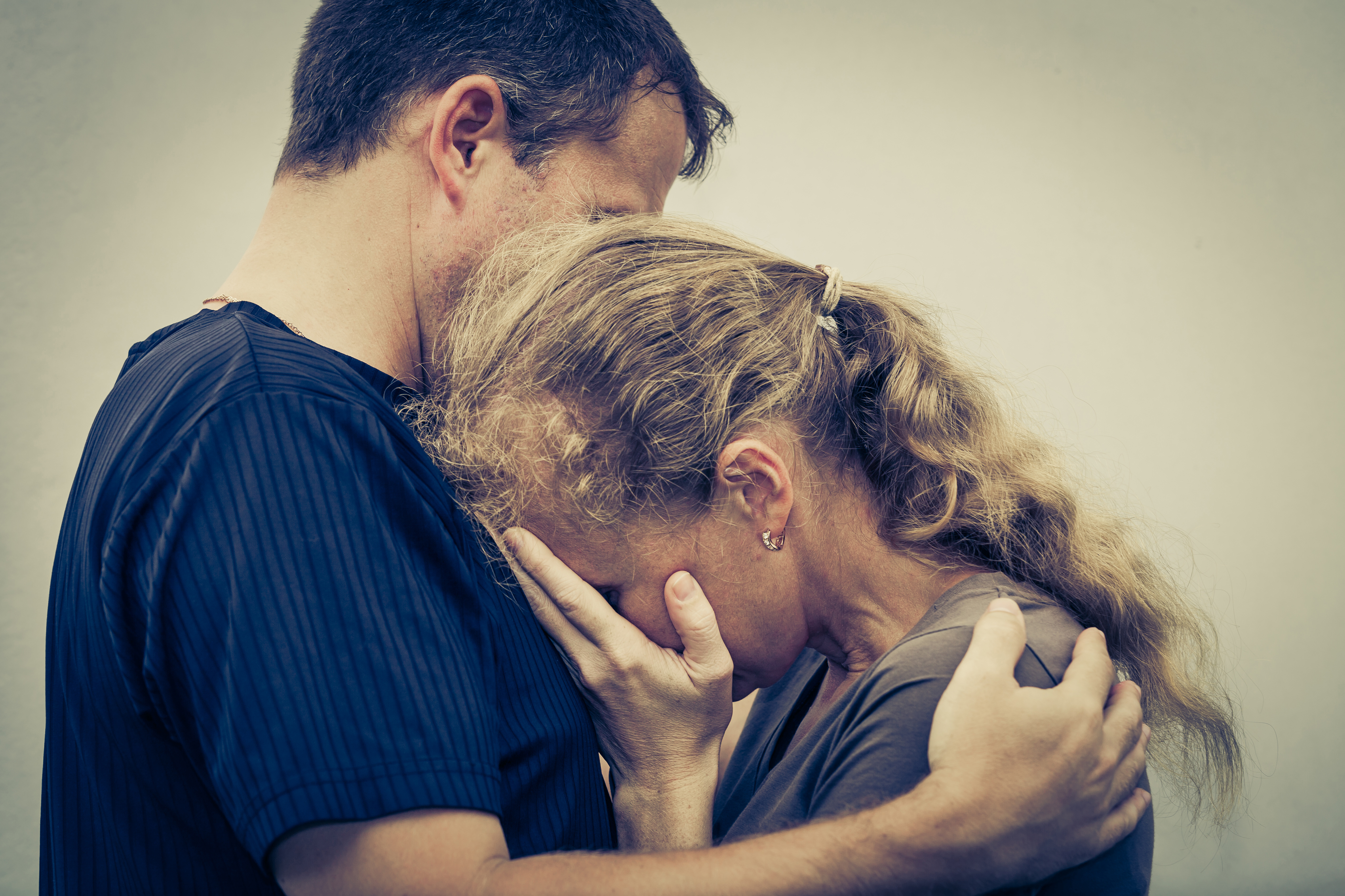Une femme en pleurs qui serre son mari dans ses bras | Source : Shutterstock