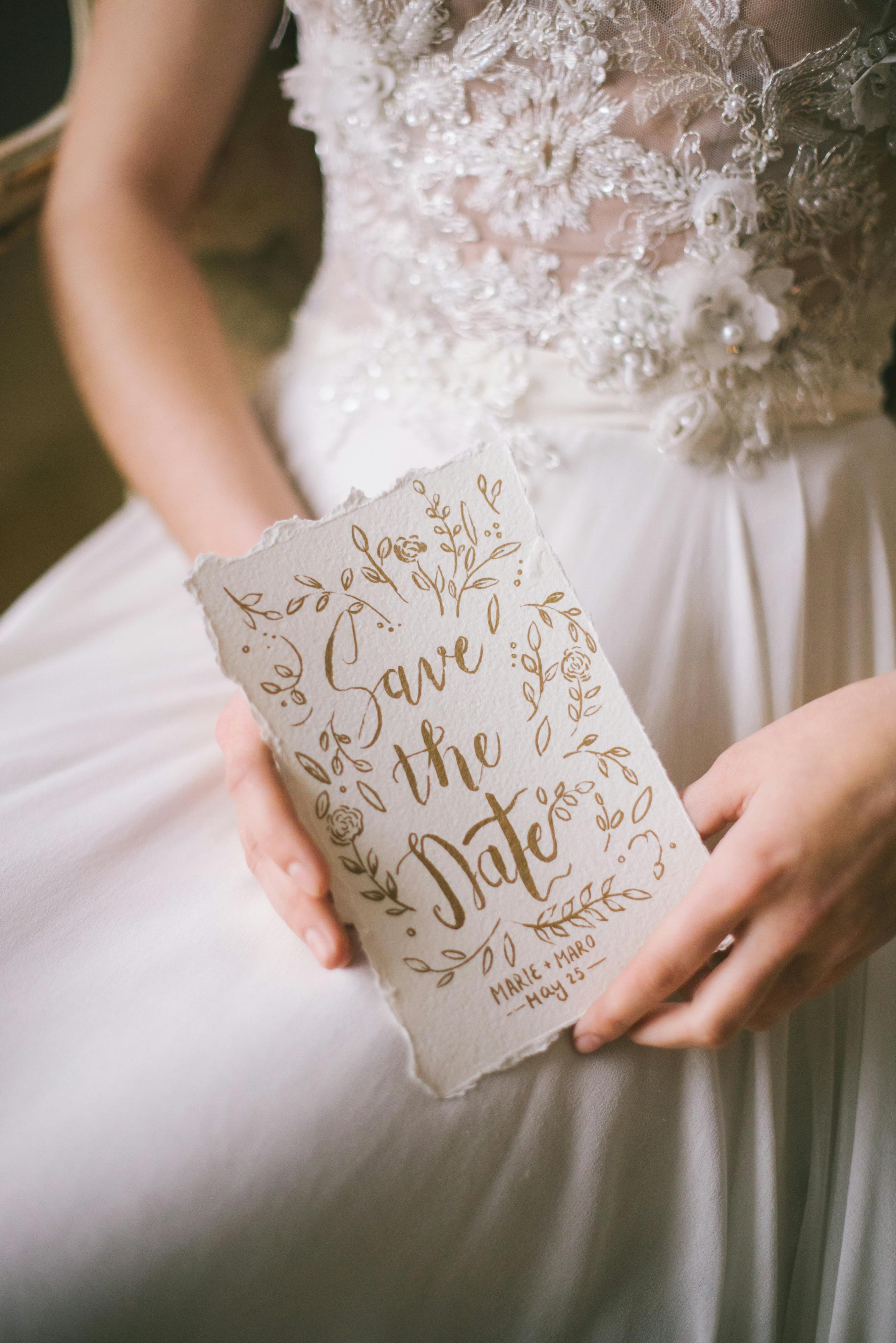 Une femme en robe blanche tenant une invitation de mariage | Source : Pexels