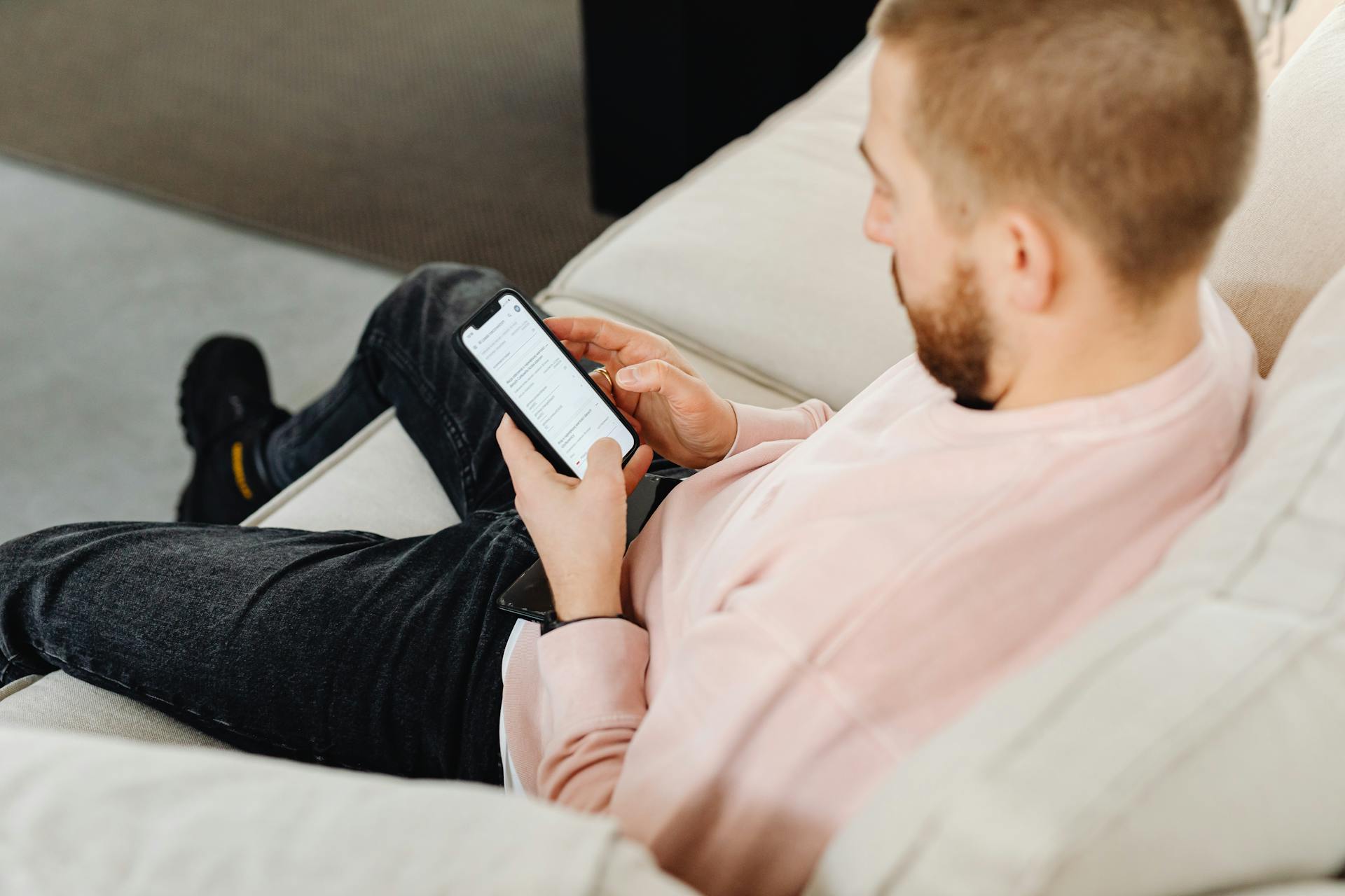 Un homme assis sur le canapé et utilisant son téléphone | Source : Pexels