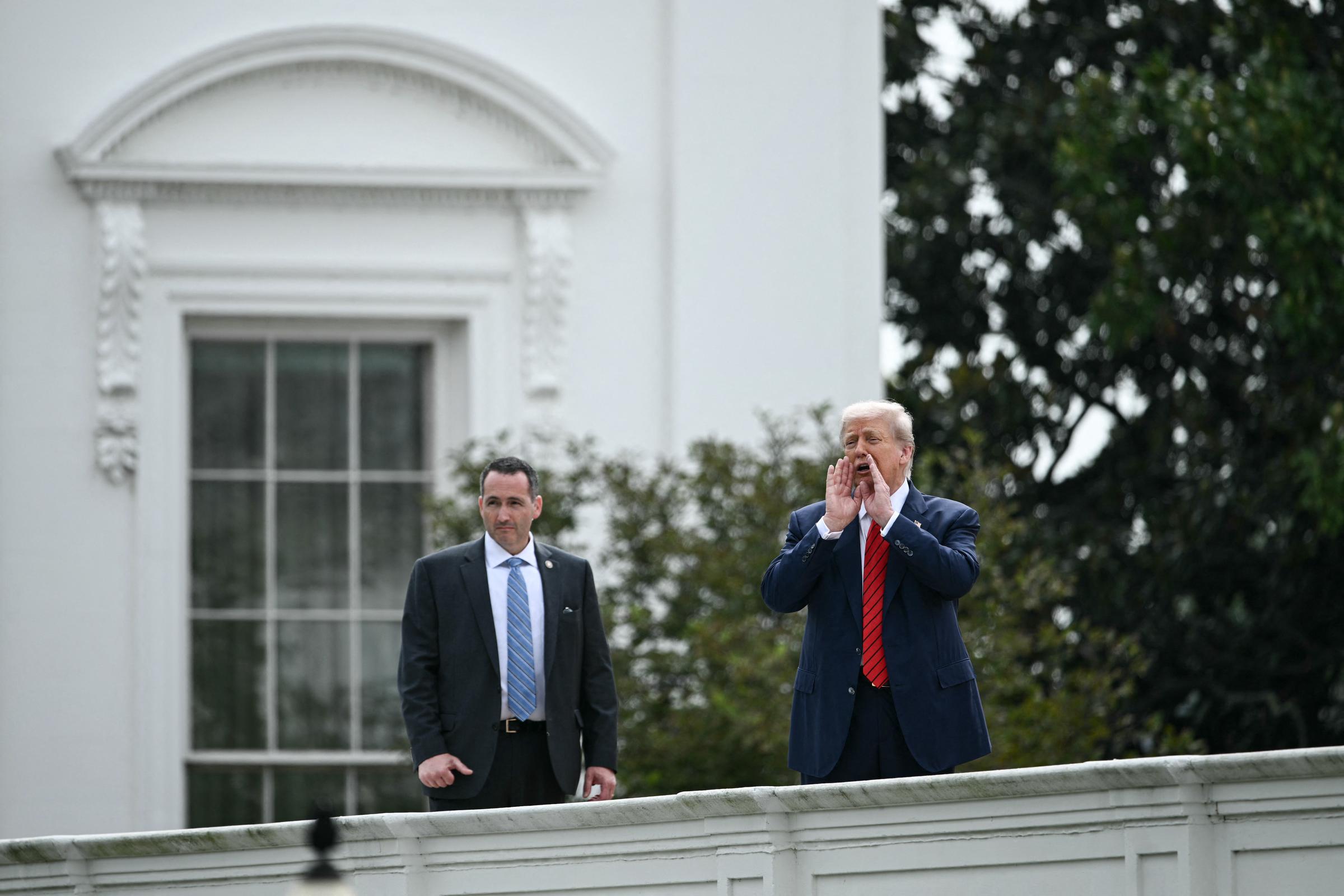 Avec son équipe de sécurité à proximité, le président Donald Trump interpelle la presse depuis le toit de l'aile ouest de la Maison Blanche à Washington, le 5 août.