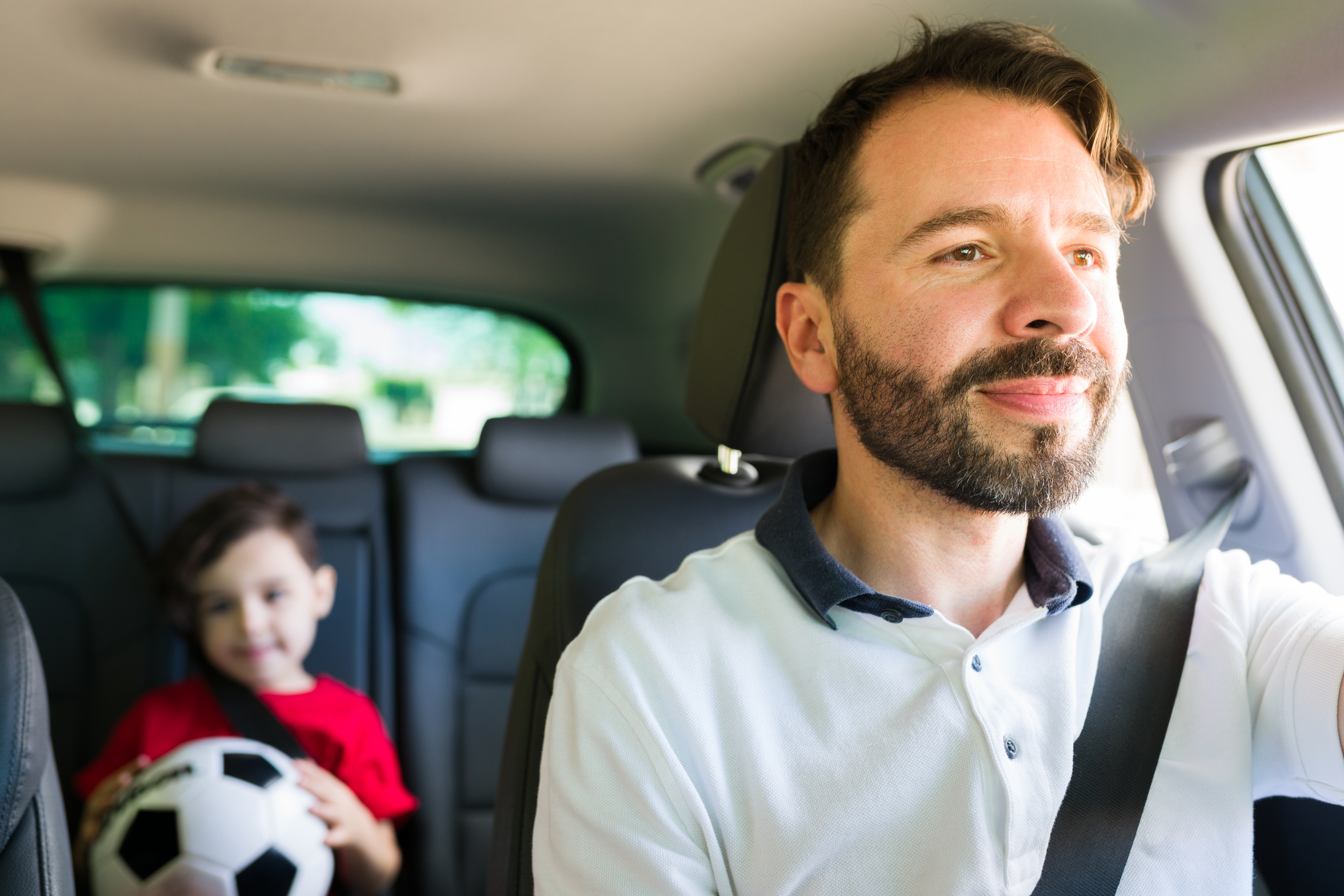 Un homme conduisant avec un petit garçon sur la banquette arrière | Source : Shutterstock