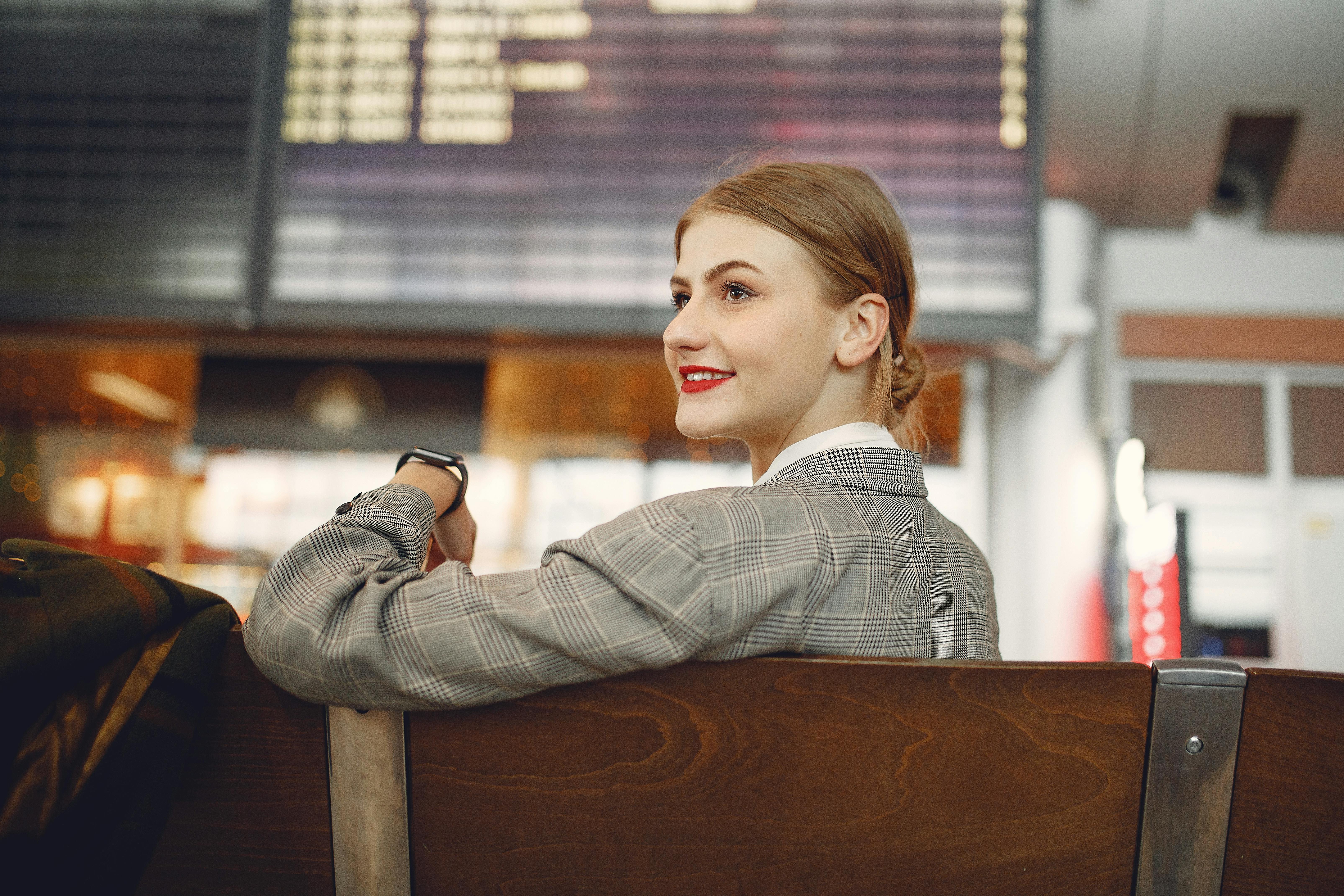 Une femme heureuse assise à l'aéroport | Source : Pexels