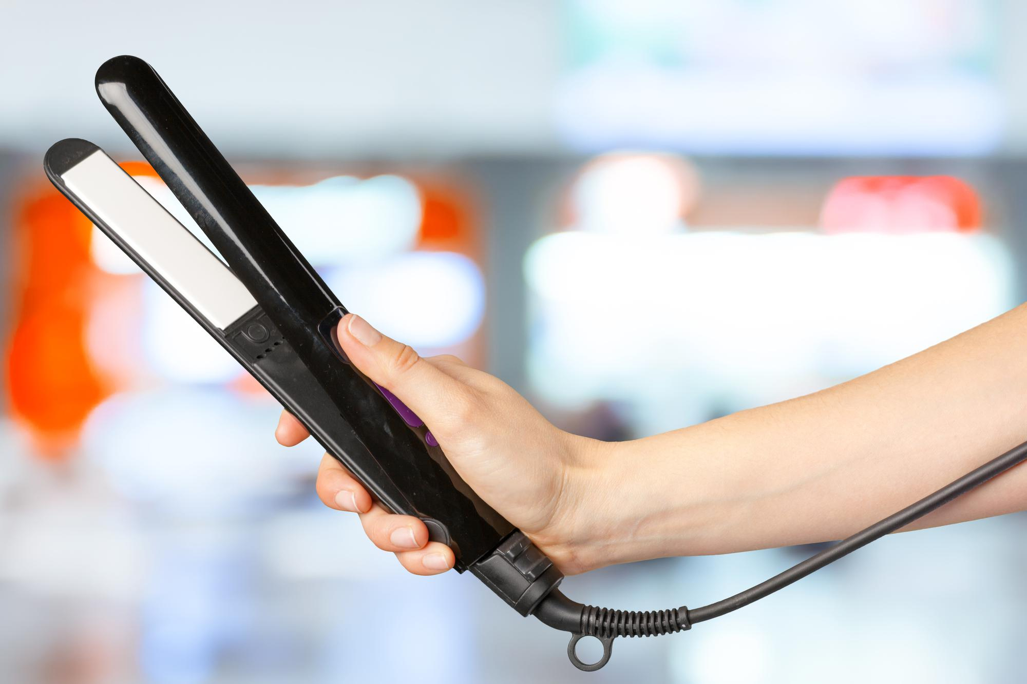 A woman holding a hair straightener | Source: Freepik