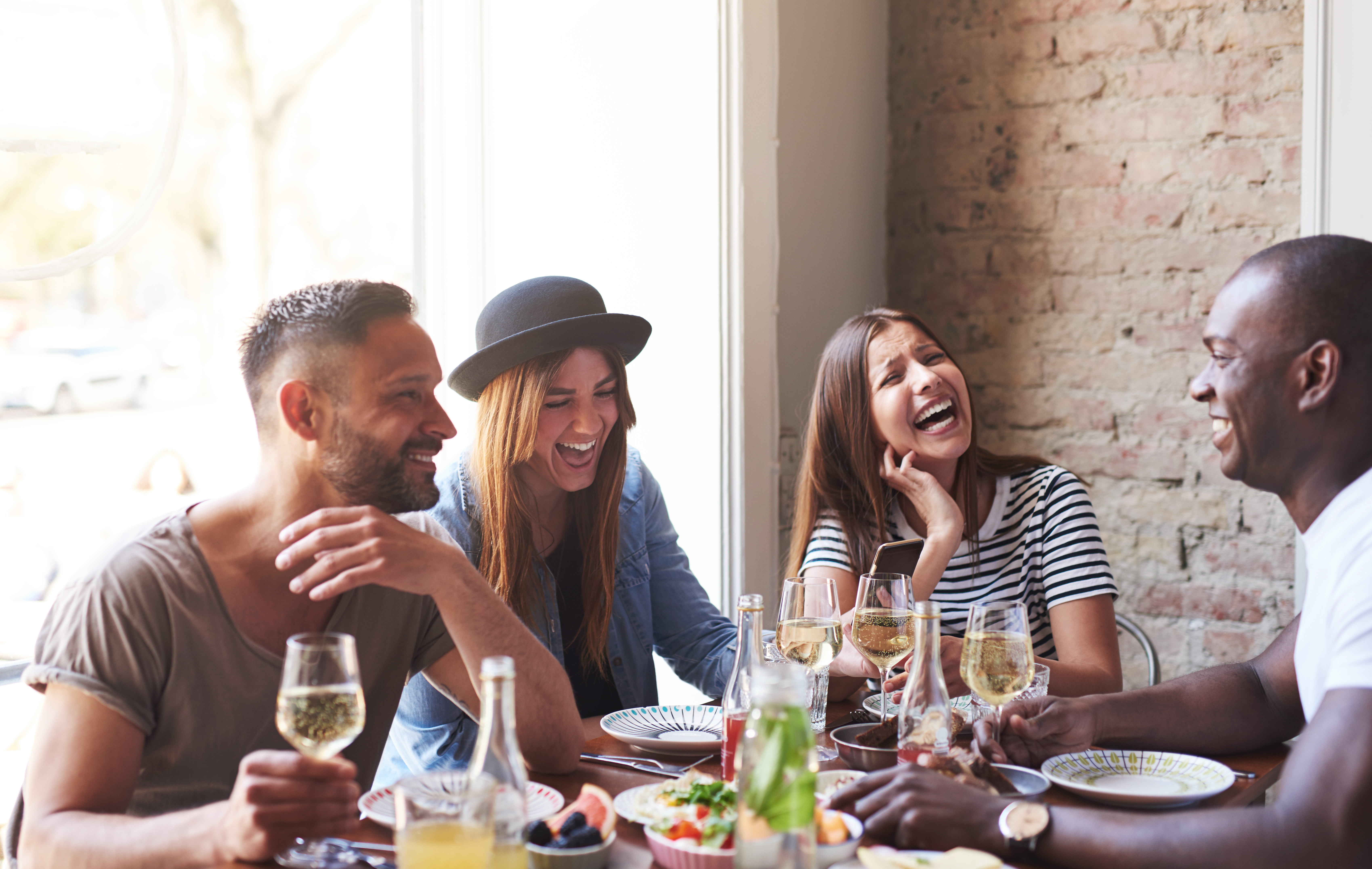 Deux hommes et deux femmes profitant de la compagnie des autres autour d'un repas | Source : Shutterstock