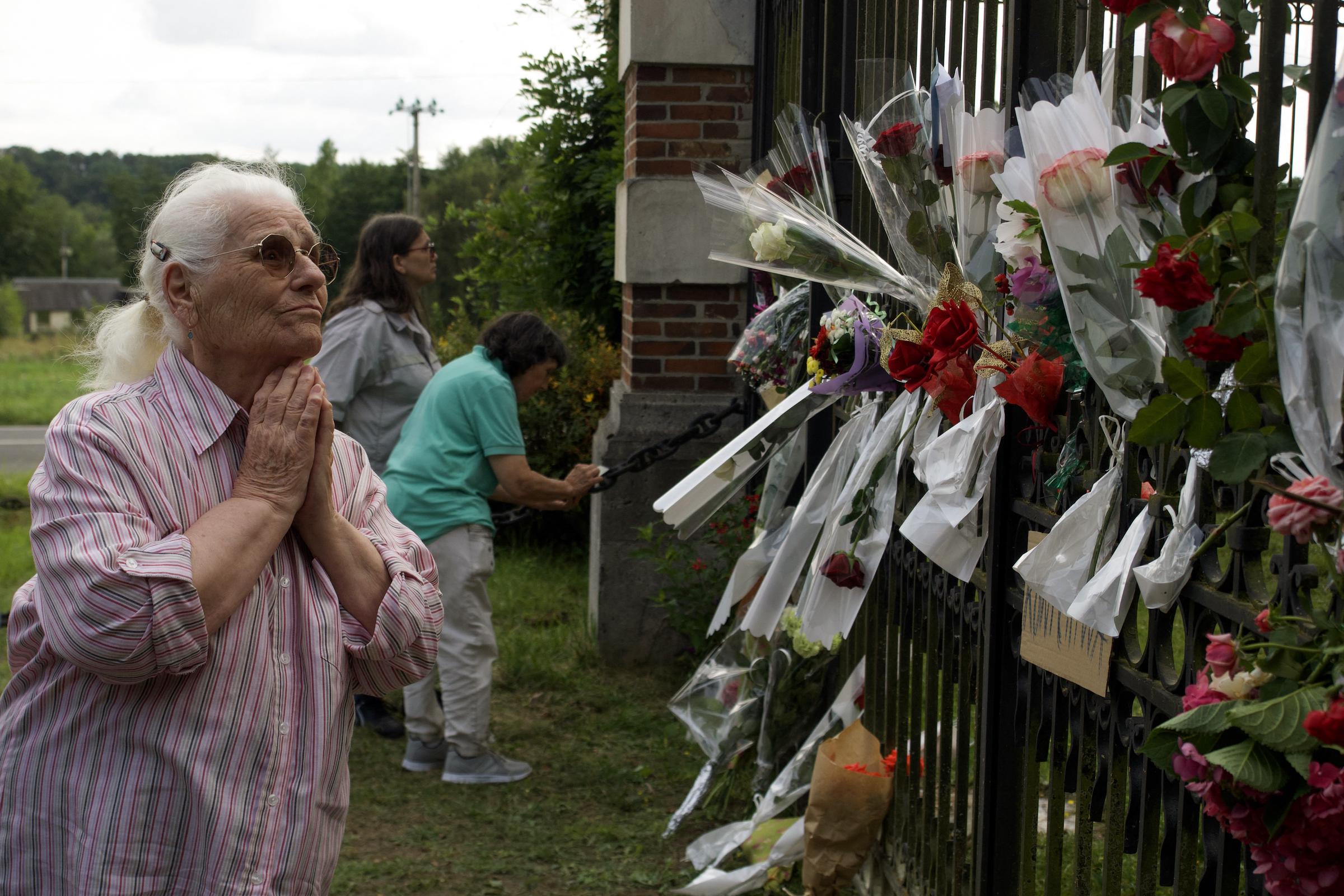 Une femme rend hommage alors que des personnes déposent des fleurs devant l'entrée de la propriété d'Alain Delon, La Brulerie, à Douchy, dans le centre de la France, le 18 août 2024. | Source : Getty Images