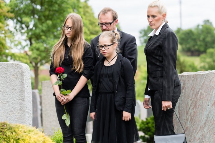  une famille en deuil dans un cimetière | Source : Shutterstock