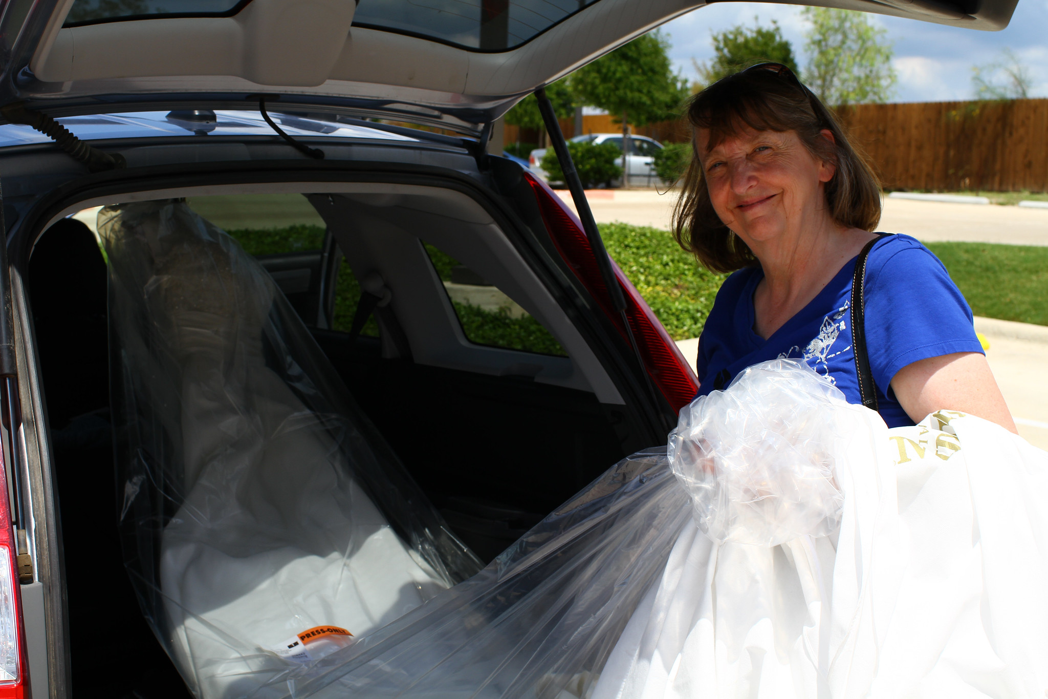 Une femme âgée sortant une robe de mariée du coffre de sa voiture | Source : Flickr