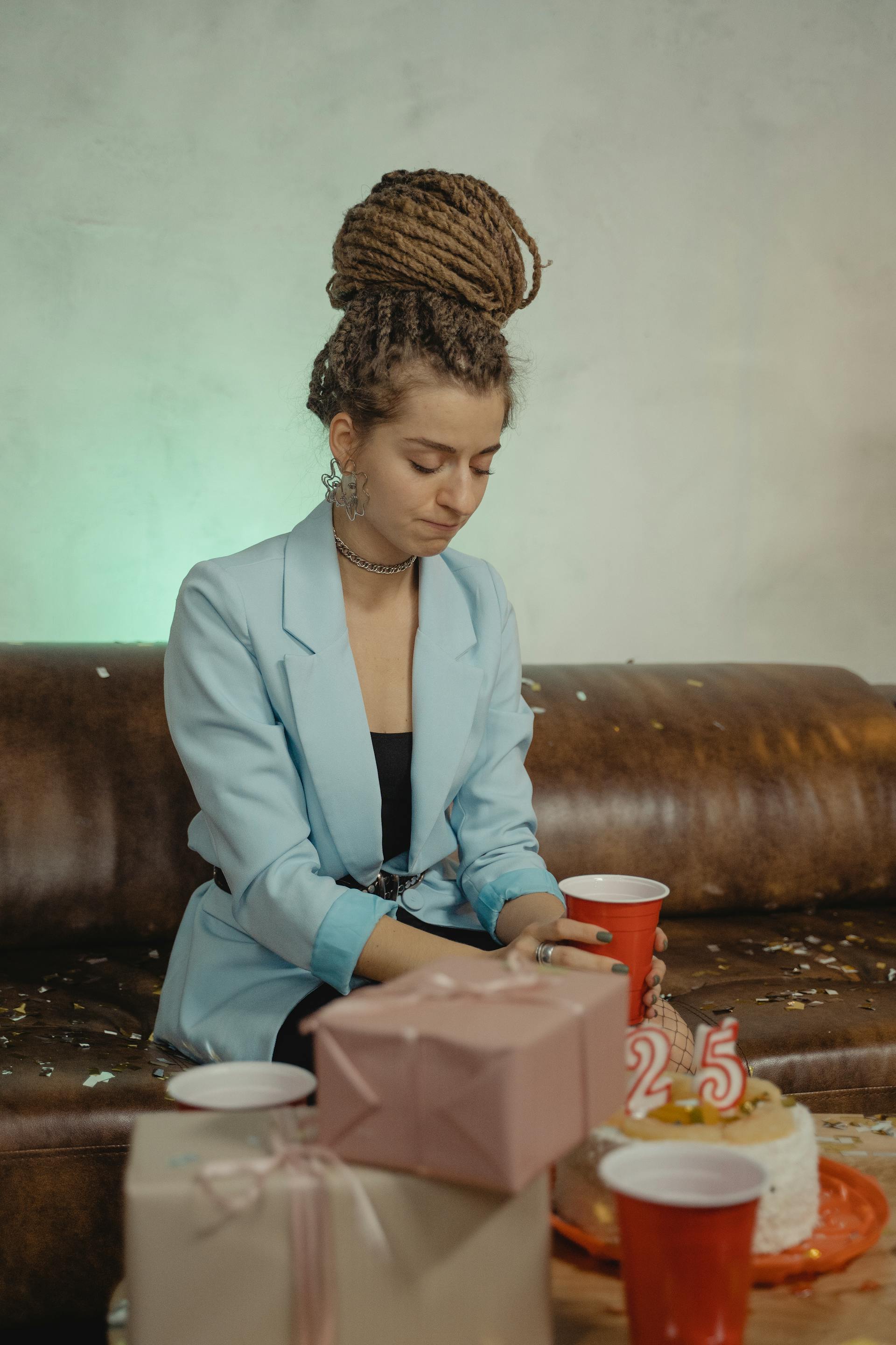 Une femme assise seule à côté d'un gâteau d'anniversaire et de cadeaux | Source : Pexels