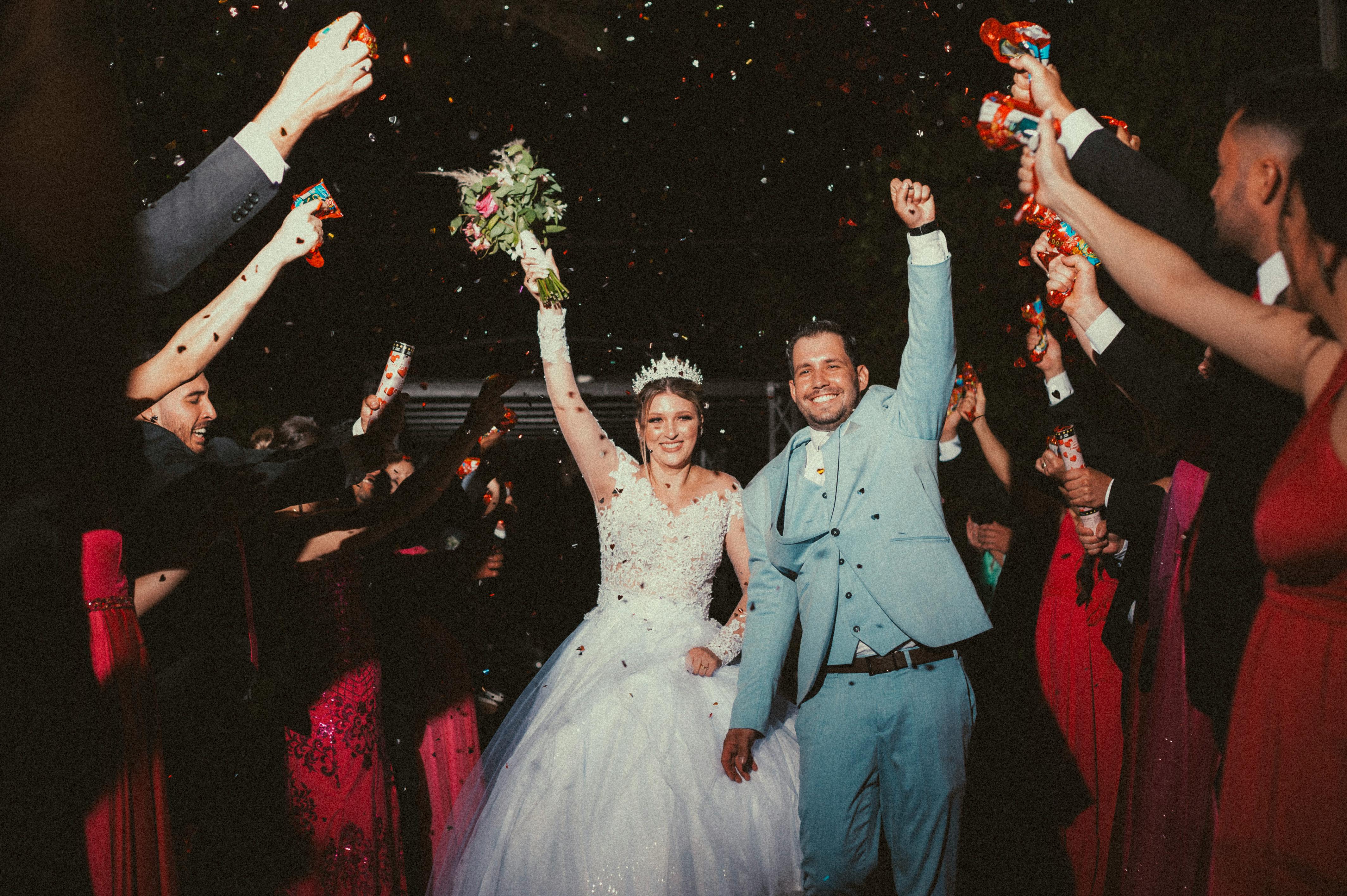 Un couple marié traversant un tunnel de mains et de confettis | Source : Pexels