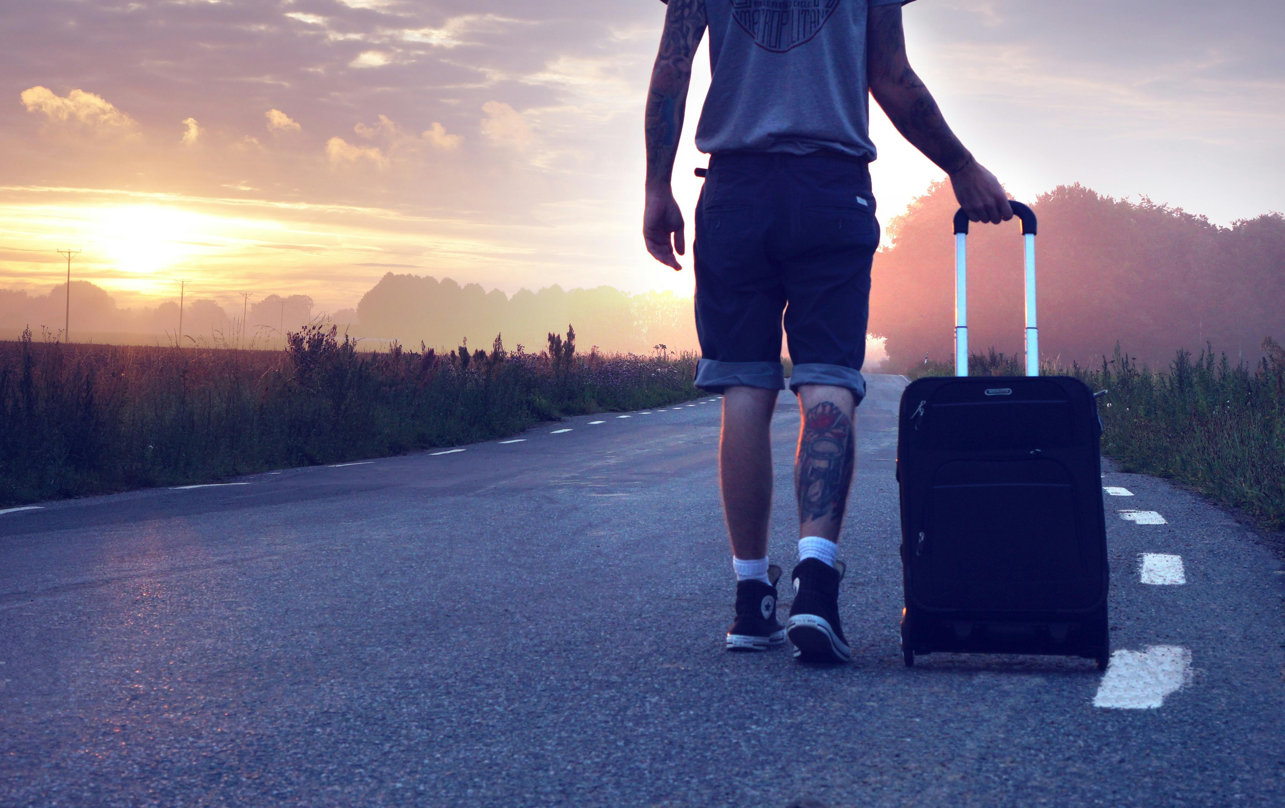 Un homme avec des bagages marchant sur la route pendant le coucher du soleil | Source : Pixabay