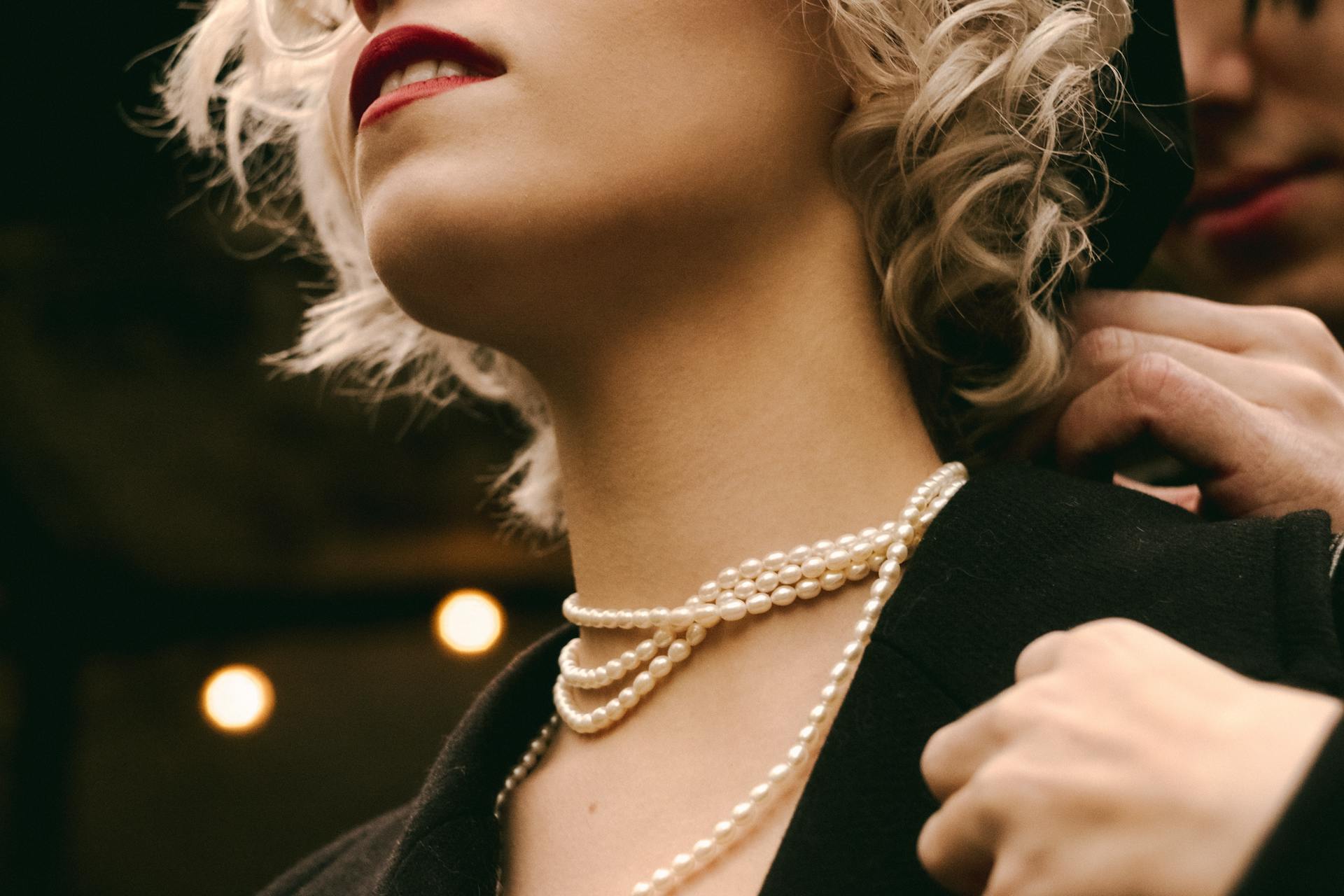 Un homme mettant un collier de perles autour du cou d'une femme | Source : Pexels