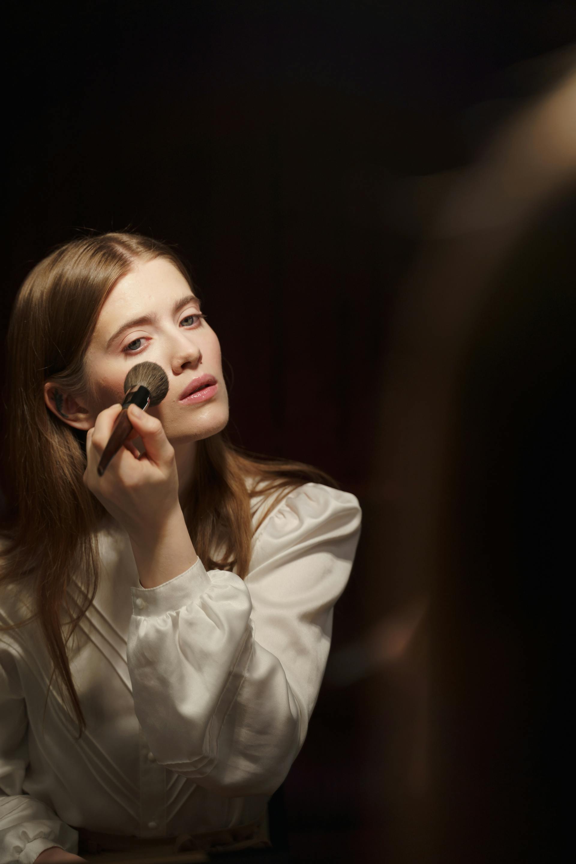 Une femme qui se maquille en se regardant dans le miroir | Source : Pexels