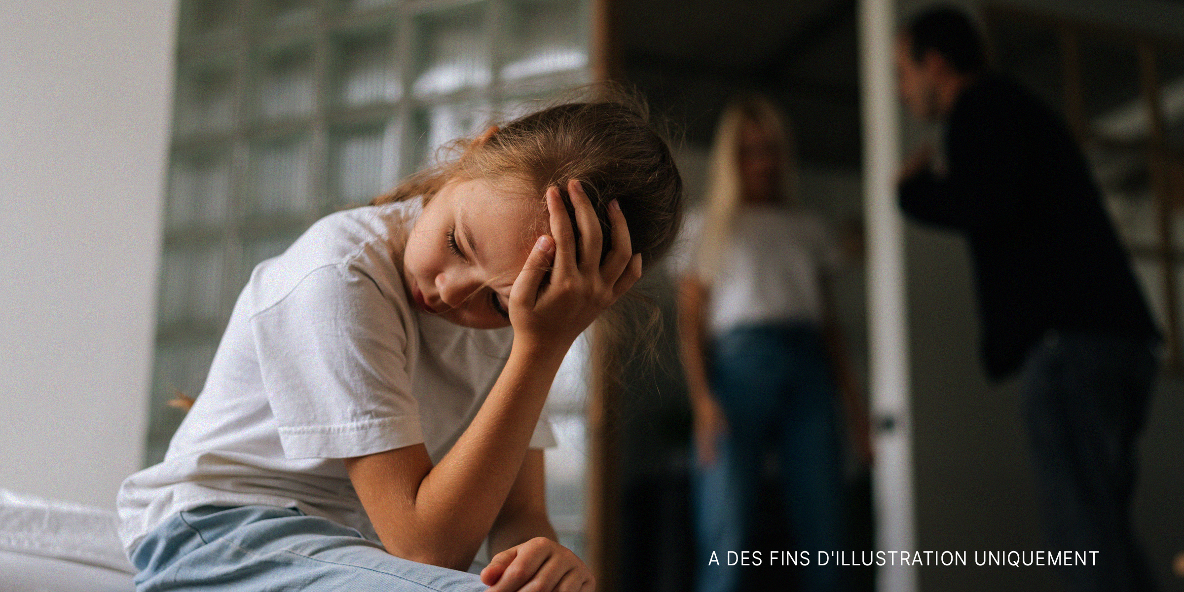 Une petite fille bouleversée tandis que ses parents se disputent en arrière-plan | Source : Shutterstock