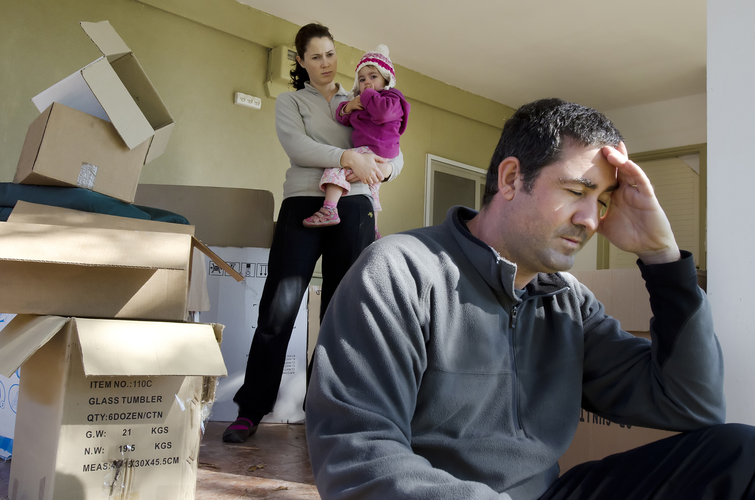 Un homme troublé avec une femme et un enfant derrière lui | Source : Shutterstock