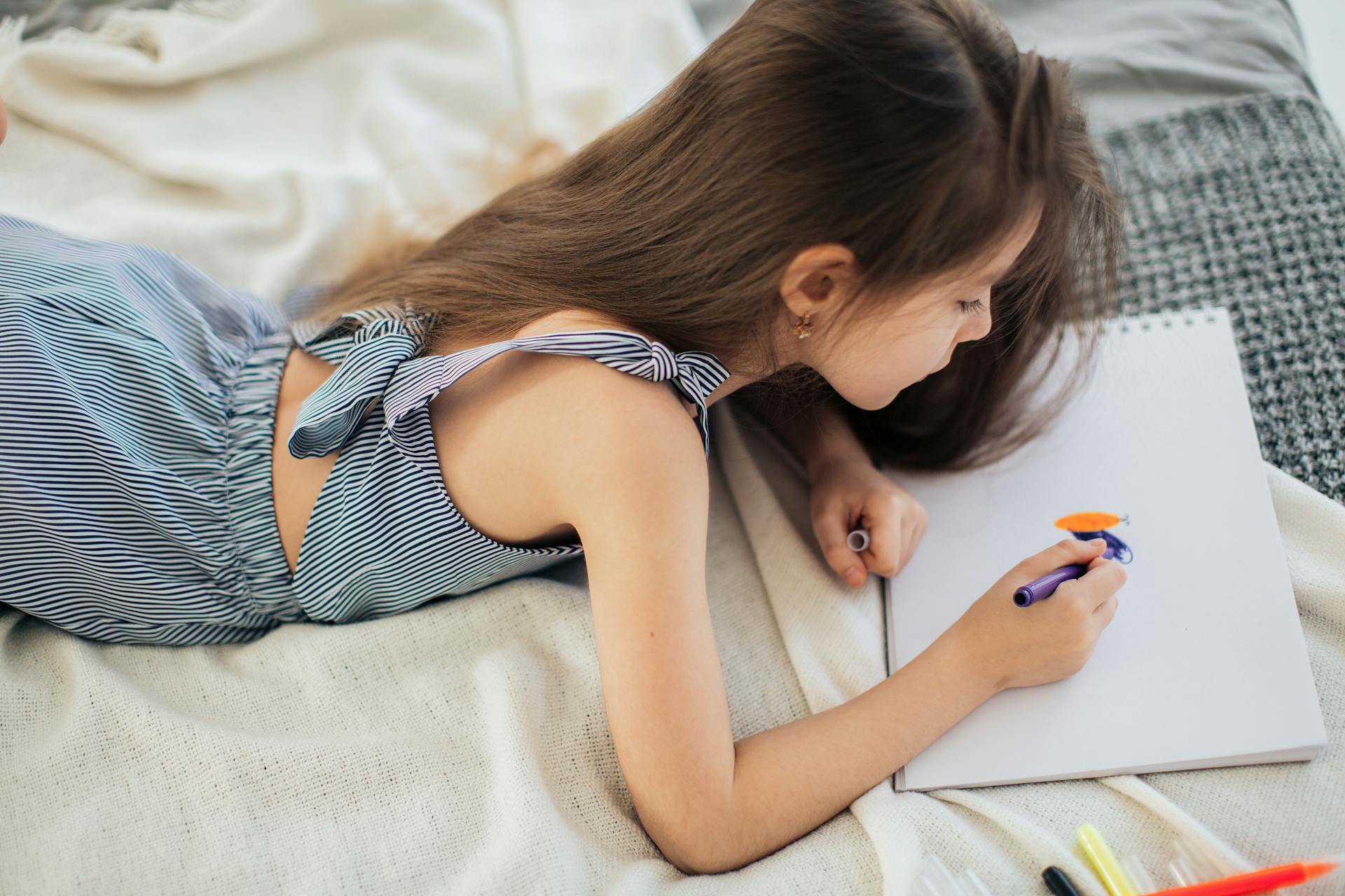 Une fille qui fait du coloriage sur son lit | Source : Pexels