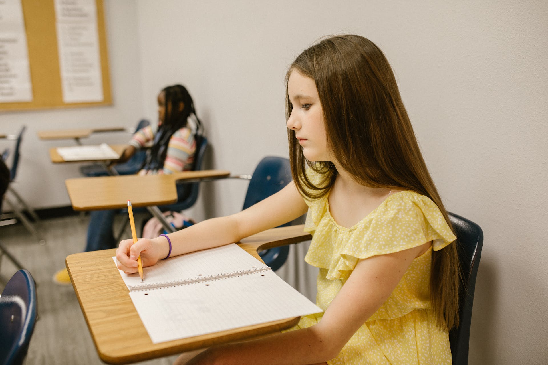Une jeune fille solitaire assise dans une salle de classe | Source : Pexels
