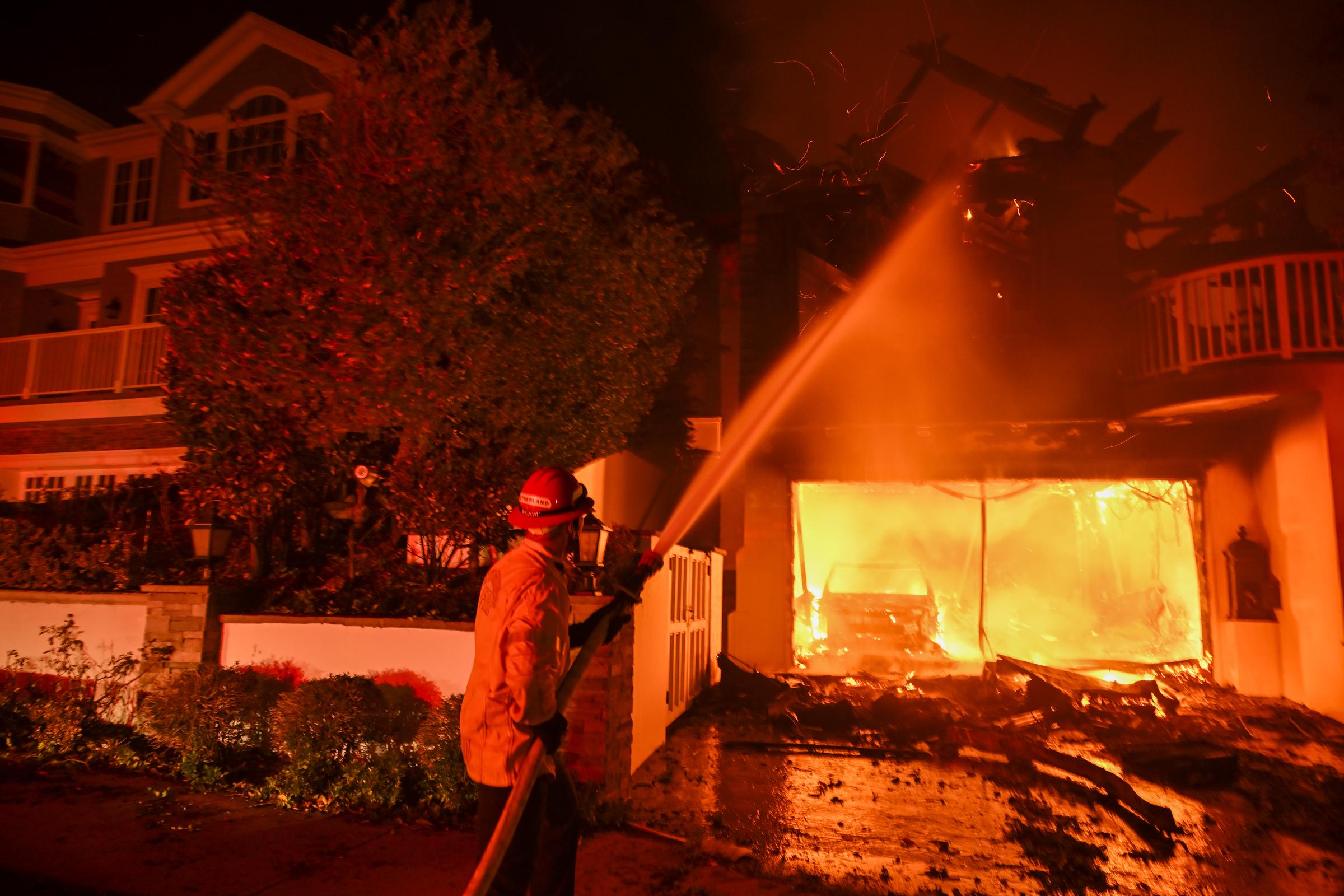 Un pompier arrose une maison prise dans un incendie à Pacific Palisades, en Californie, le 8 janvier 2025. | Source : Getty Images