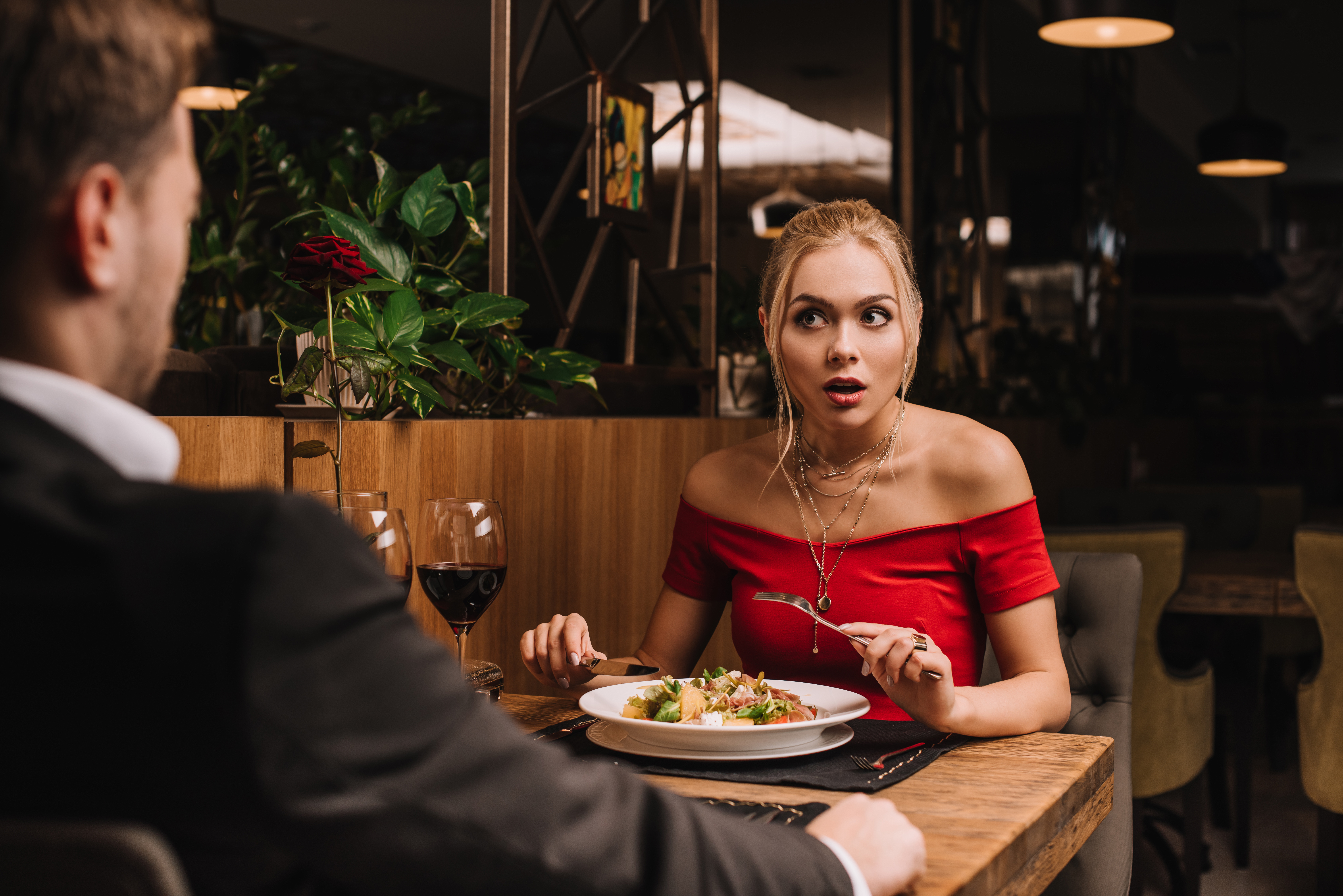 Une jeune femme regarde l'homme en état de choc pendant le dîner | Source : Shutterstock
