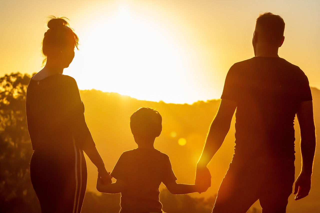 Un couple avec son enfant regardant le coucher de soleil | Source : Pixabay