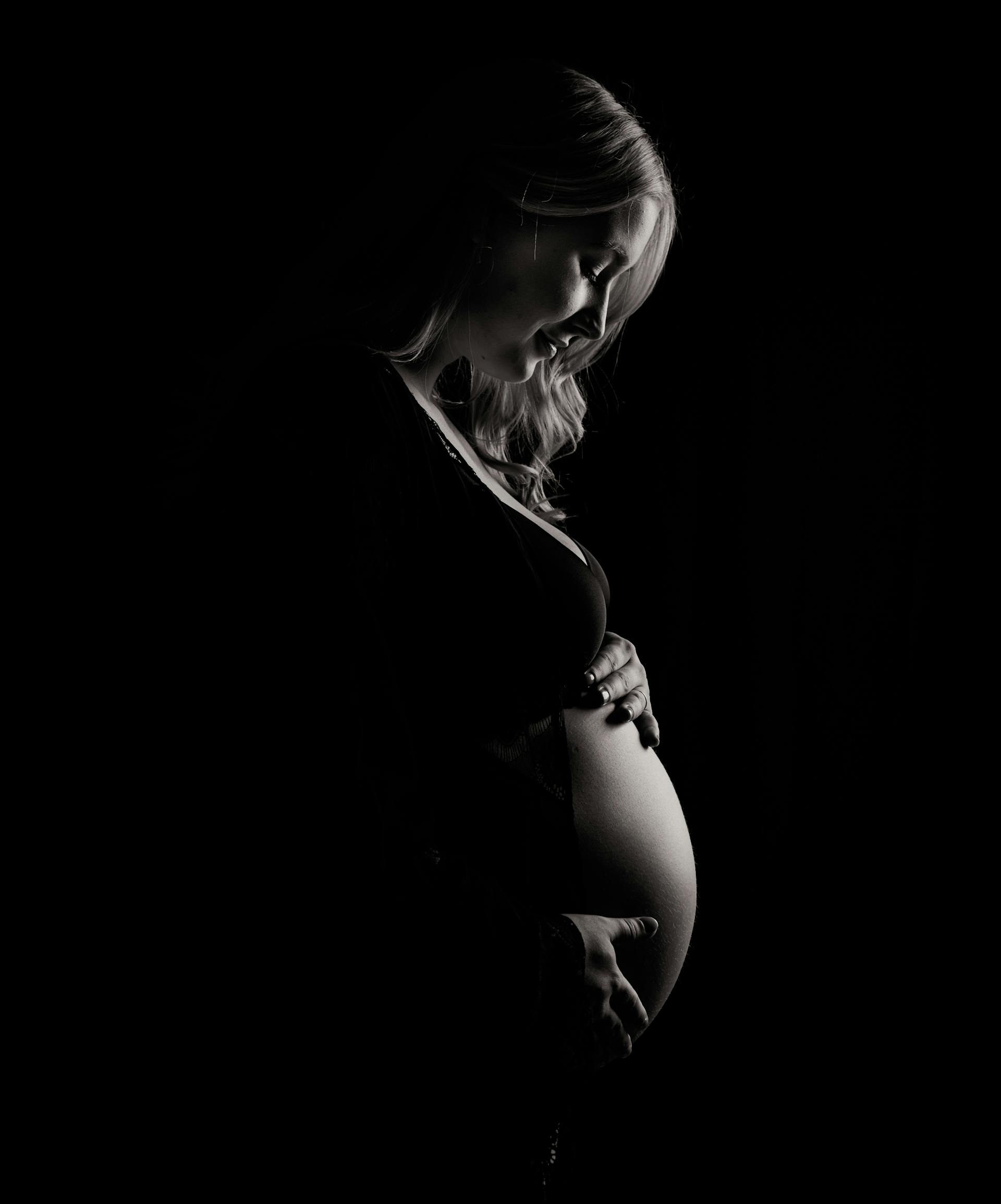 Une photo en niveaux de gris d'une femme enceinte tenant son baby bump | Source : Pexels