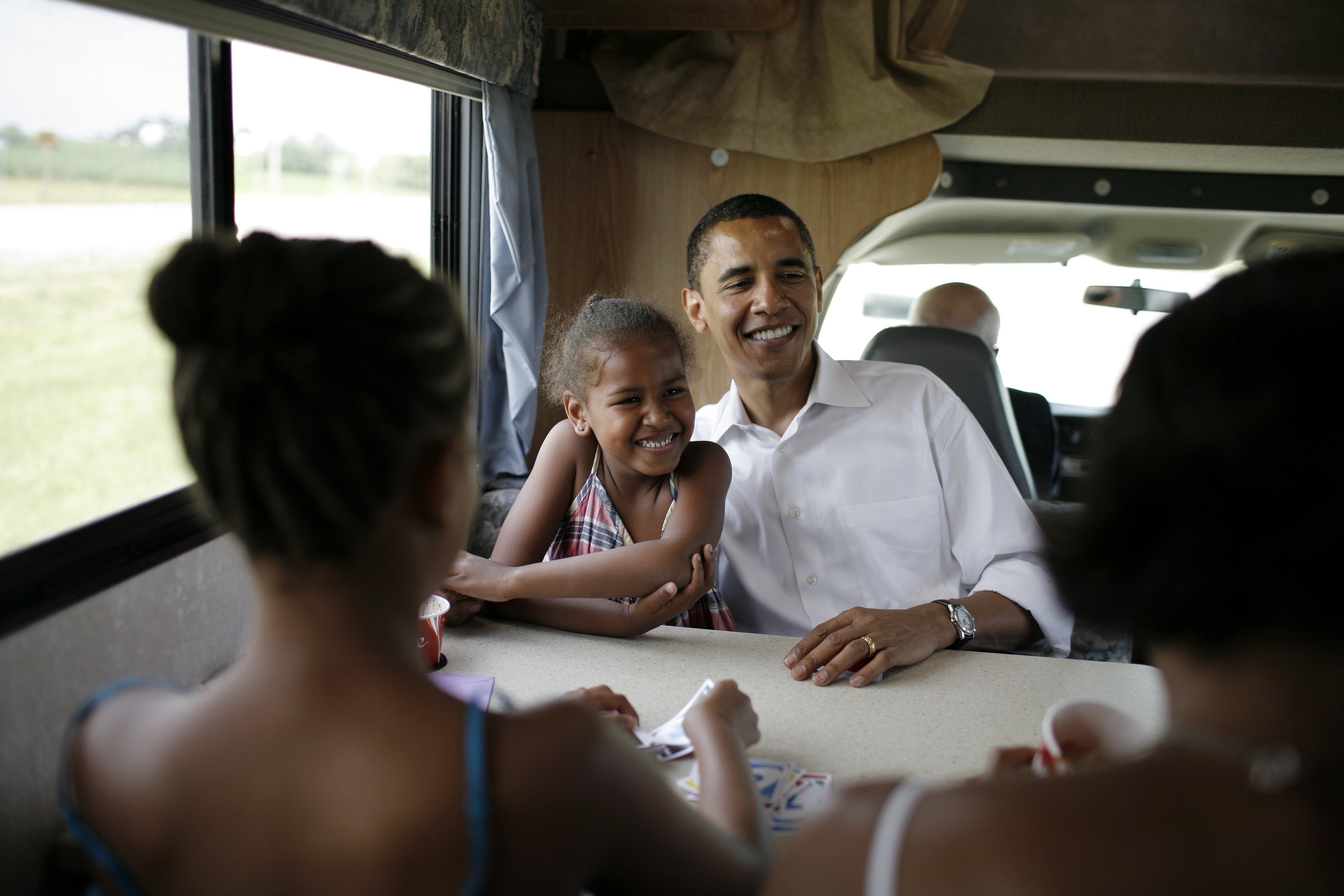 Michelle, Malia, Sasha et Barack Obama jouent aux cartes dans leur camping-car lors d'une tournée de campagne entre Oskaloosa et Pella, dans l'Iowa, le 4 juillet 2007. | Source : Getty Images