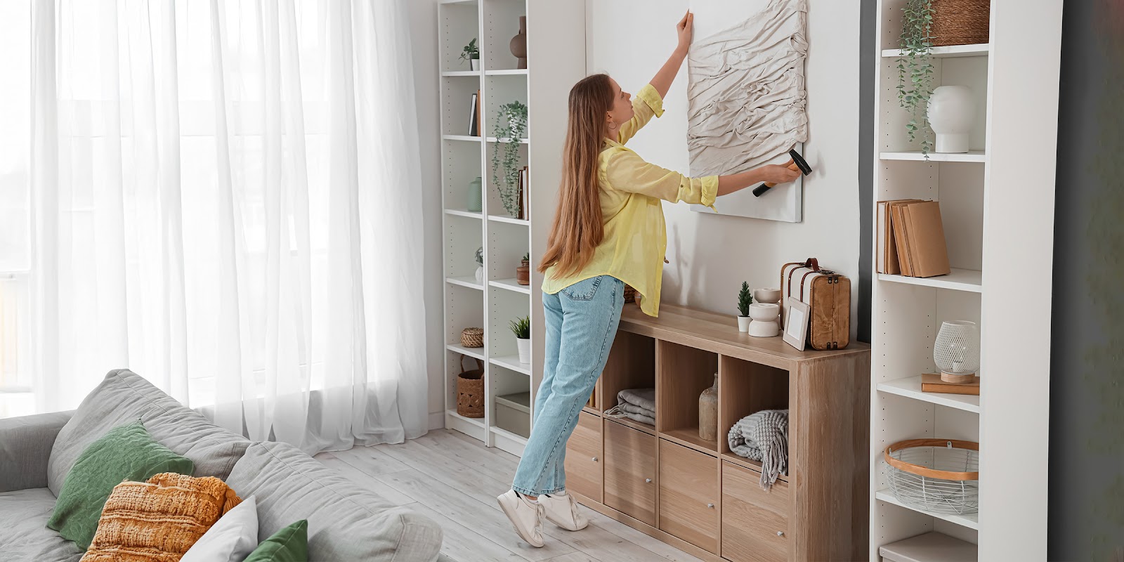 Une femme qui accroche un tableau | Source : Shutterstock