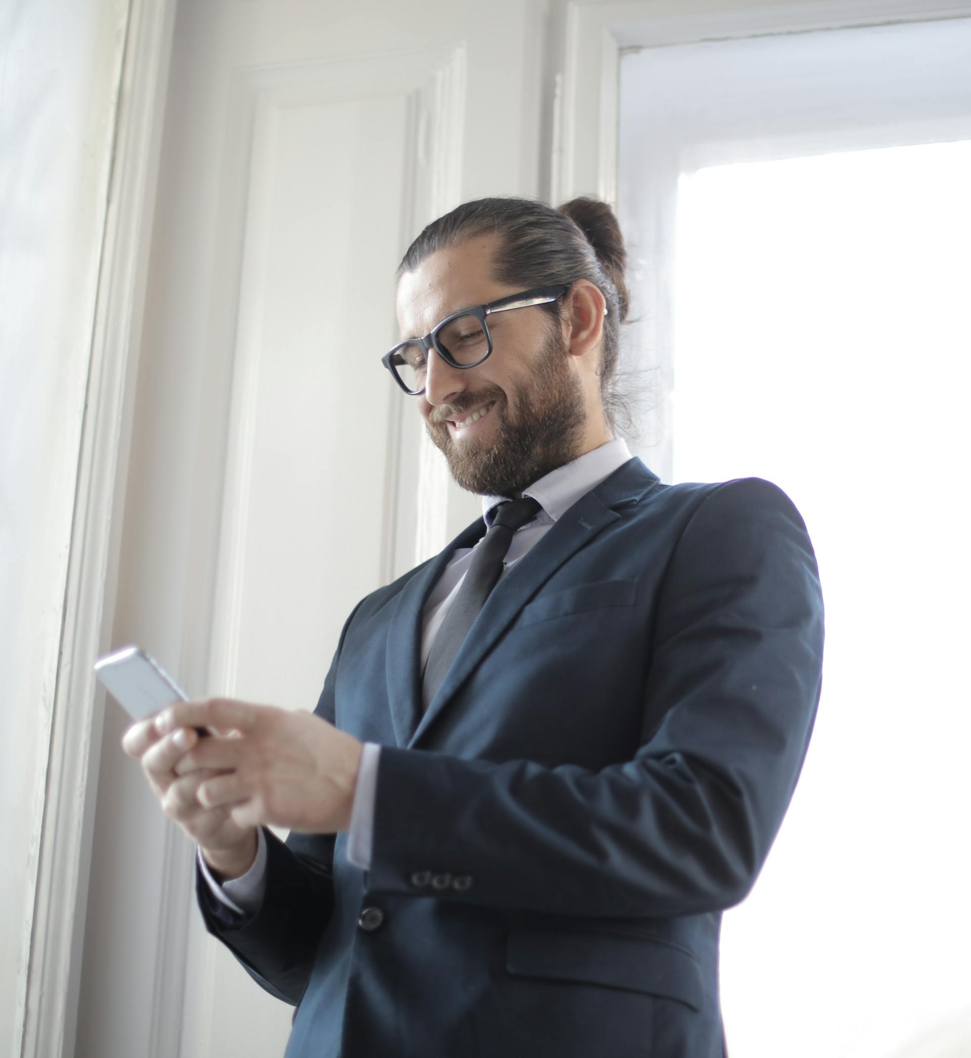 Un homme qui sourit à son téléphone | Source : Pexels