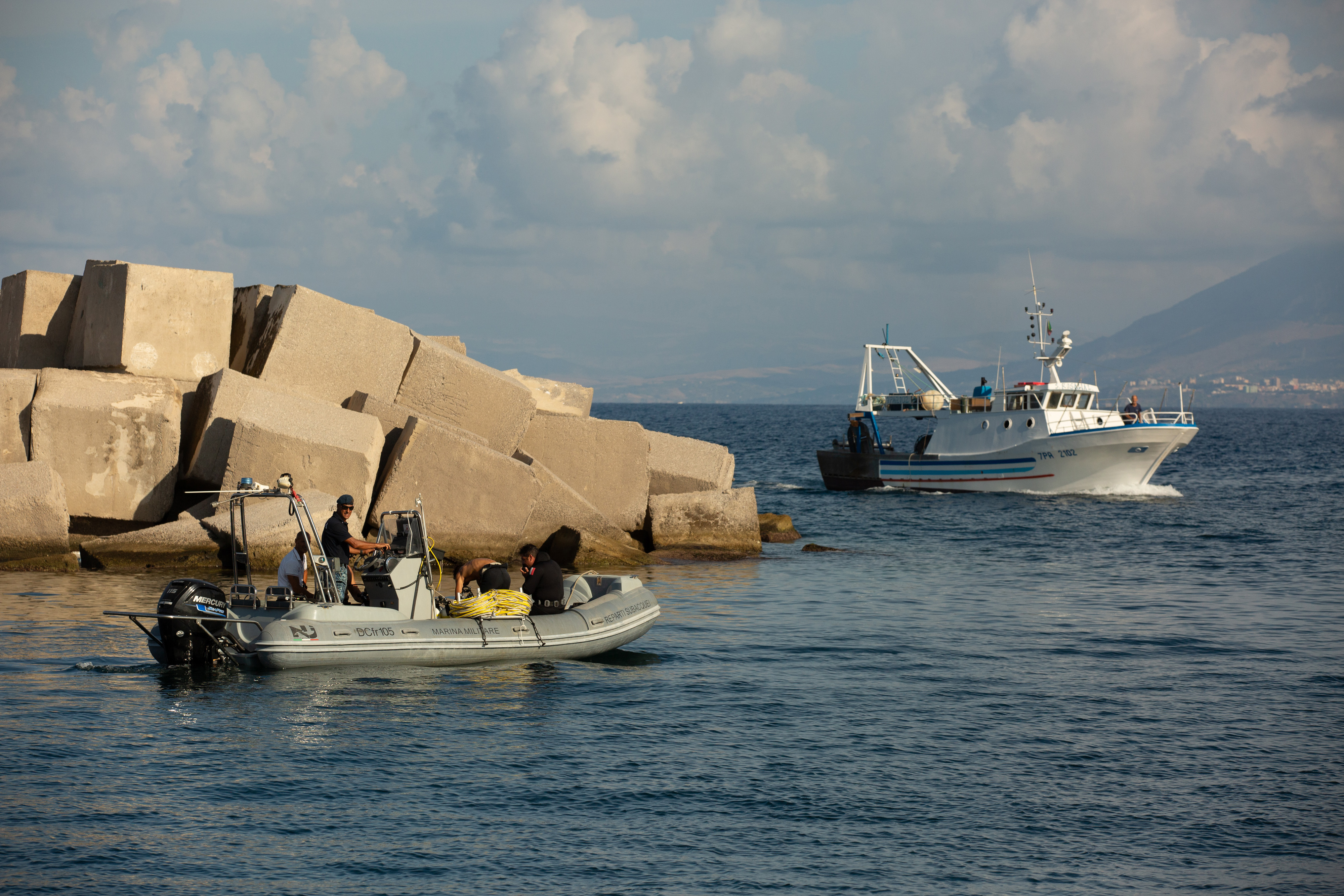 Un bateau de pêche passant devant des plongeurs pendant les opérations de recherche du yacht de luxe Bayesian de Mike Lynch, au large de Porticello, en Italie, le 22 août 2024. | Source : Getty Images