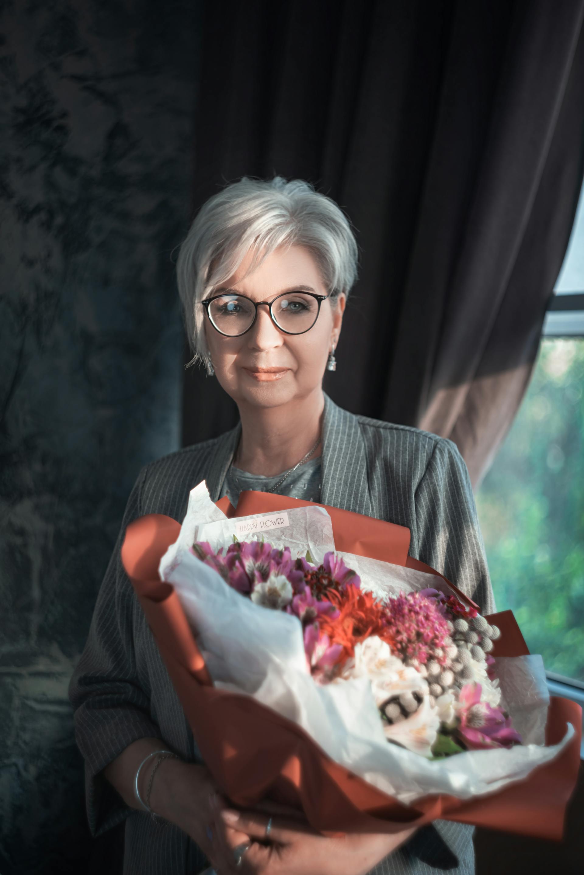 Une femme souriante tenant un bouquet de fleurs | Source : Pexels