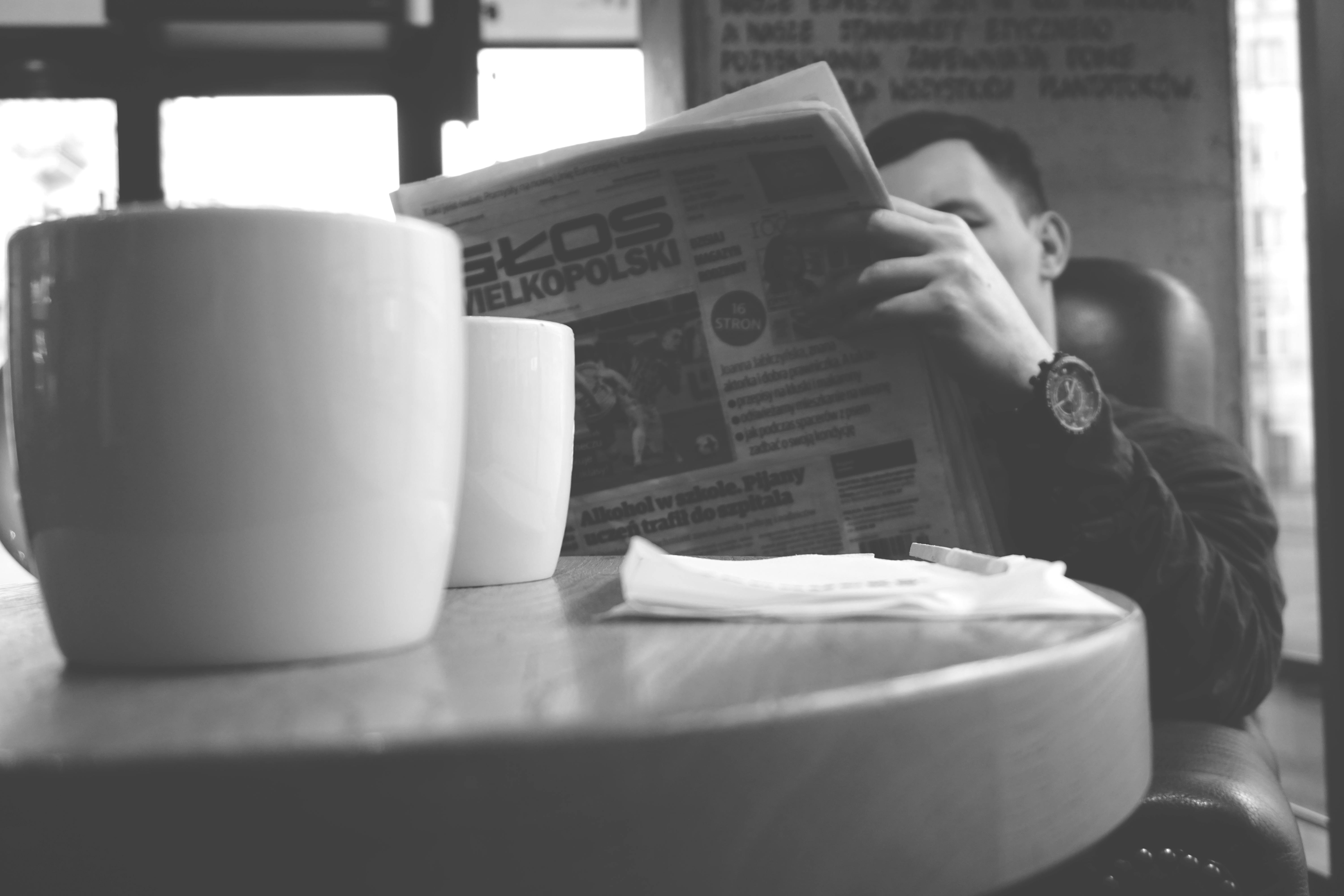 Un homme lisant un journal à une table | Source : Pexels