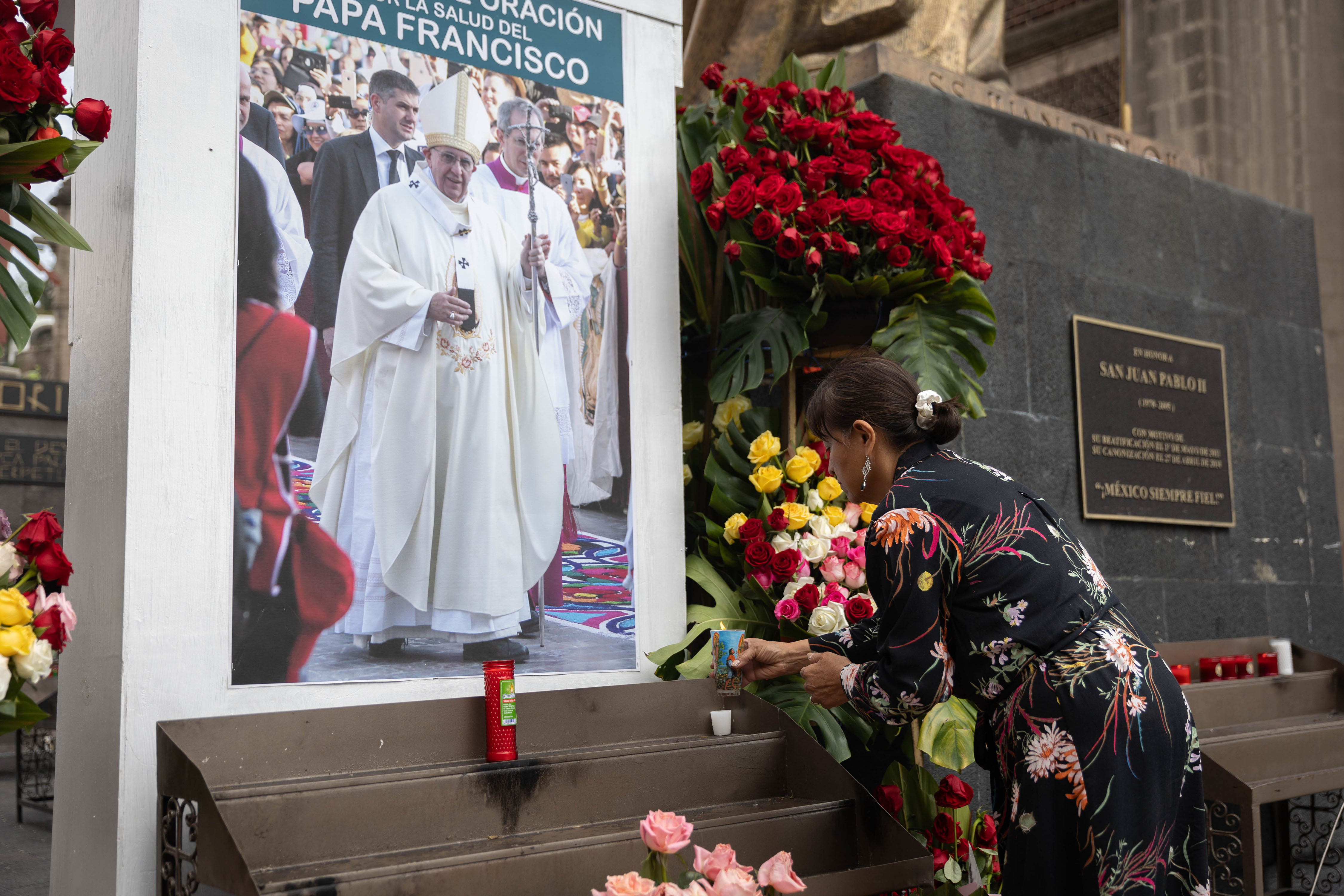 Une femme plaçant une bougie devant une image du pape François à l'extérieur de la basilique de Guadalupe, à Mexico, au Mexique, le 23 février 2025. | Source : Getty Images