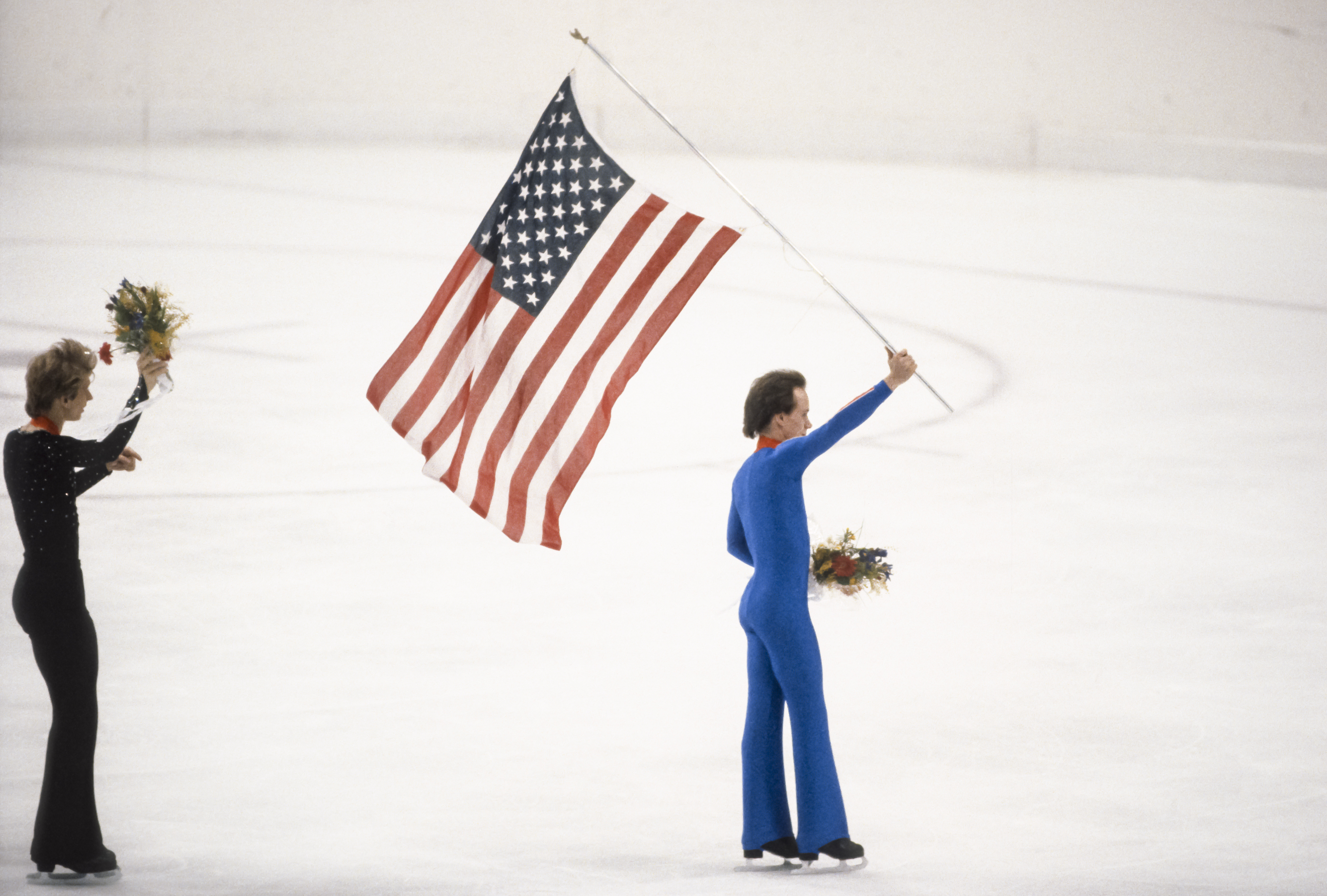 Scott Hamilton (USA) patine avec le drapeau américain après la cérémonie de remise des médailles de l'épreuve du simple messieurs aux Jeux olympiques d'hiver de 1984 à Sarajevo, Yougoslavie, le 16 février 1984 | Source : Getty Images