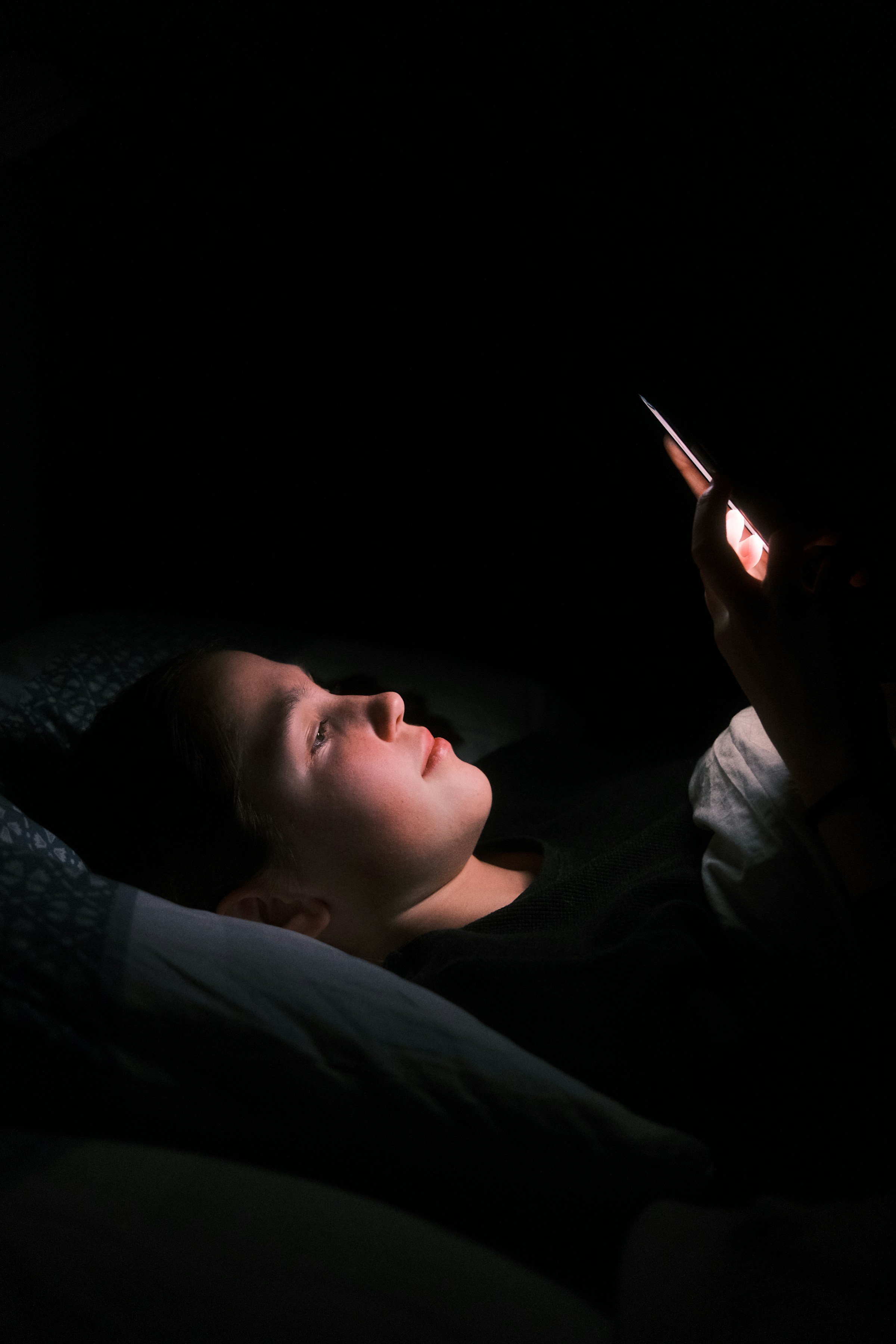 Une femme utilisant son téléphone dans son lit la nuit | Source : Unsplash