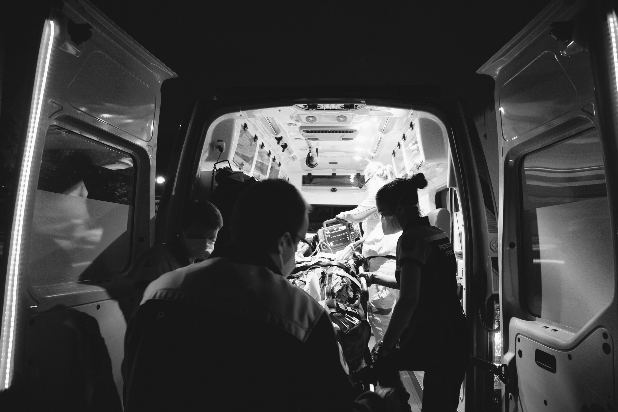 Des ambulanciers soulèvent un lit roulant dans une ambulance | Source : Unsplash