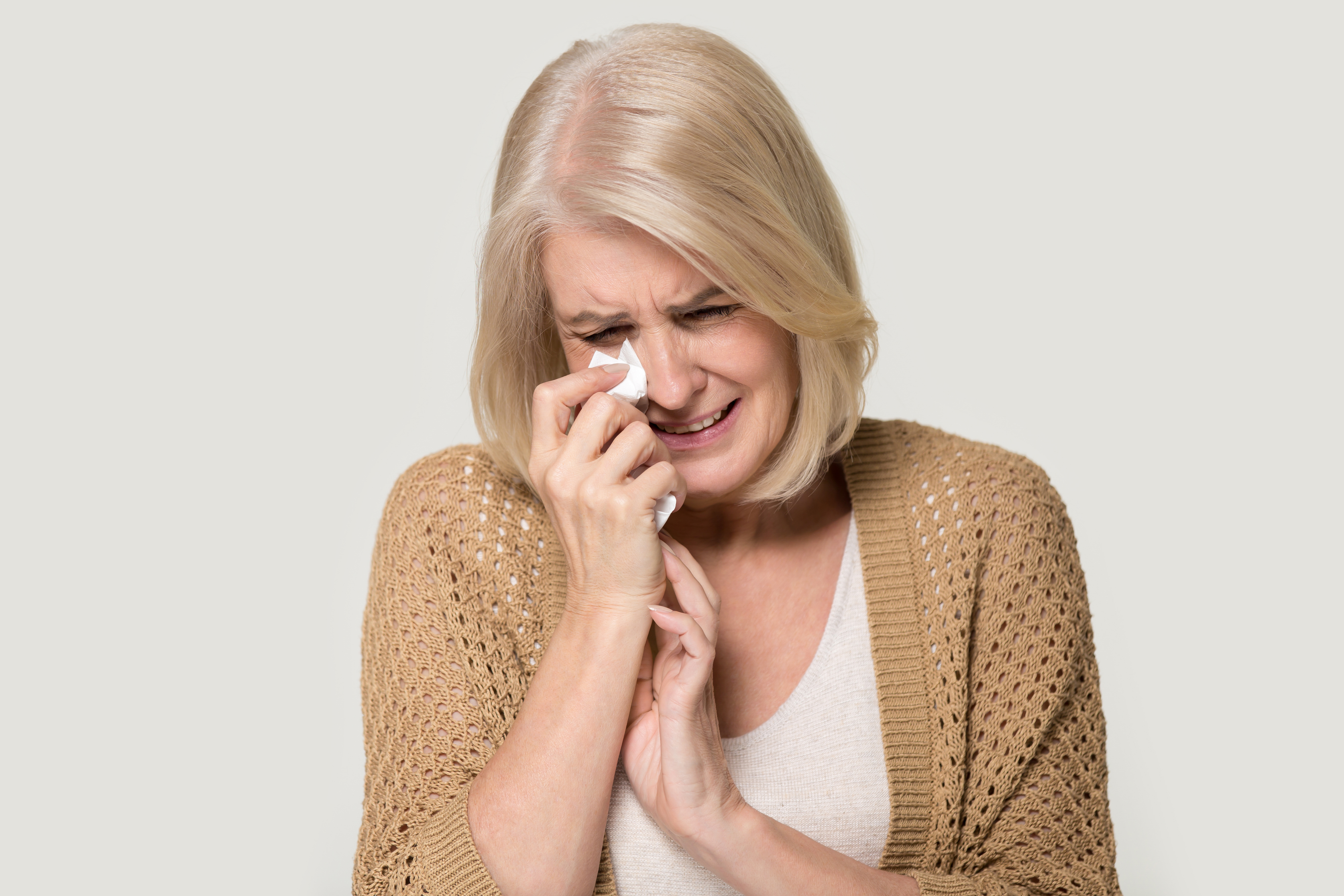 Une dame âgée en pleurs essuie ses larmes avec son mouchoir | Source : Shutterstock