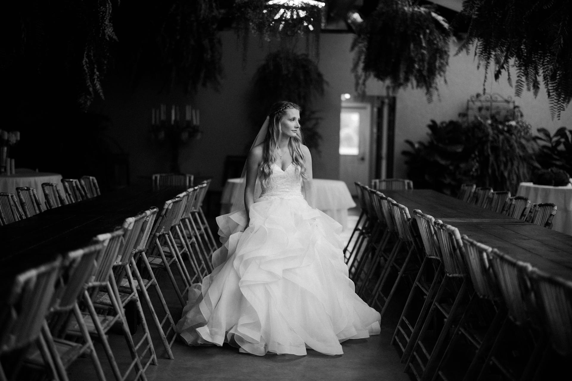 Une photo en niveaux de gris d'une mariée debout marchant le long d'une rangée de chaises vides | Source : Pexels