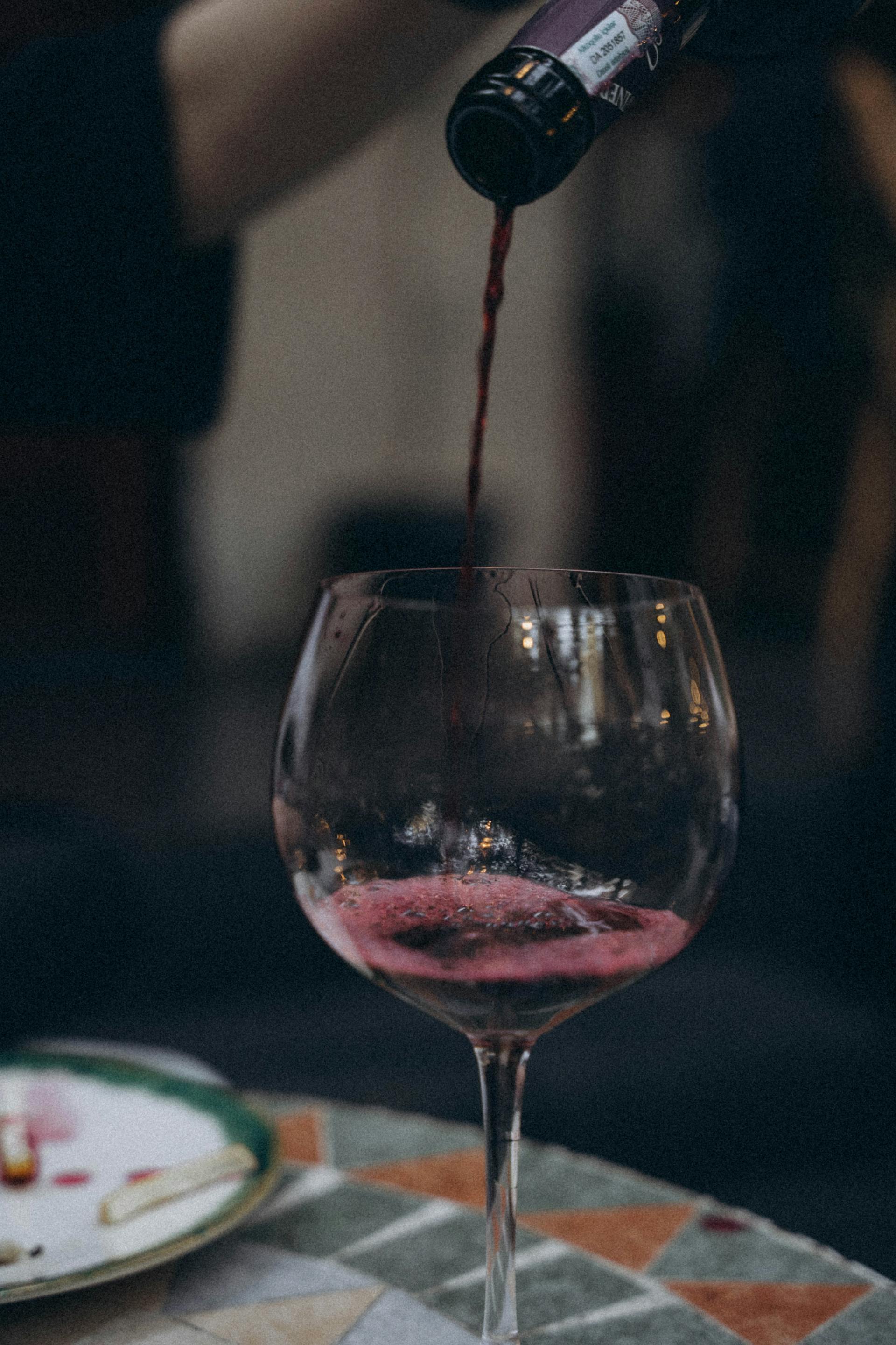 Gros plan sur une personne qui verse du vin rouge dans un verre | Source : Pexels