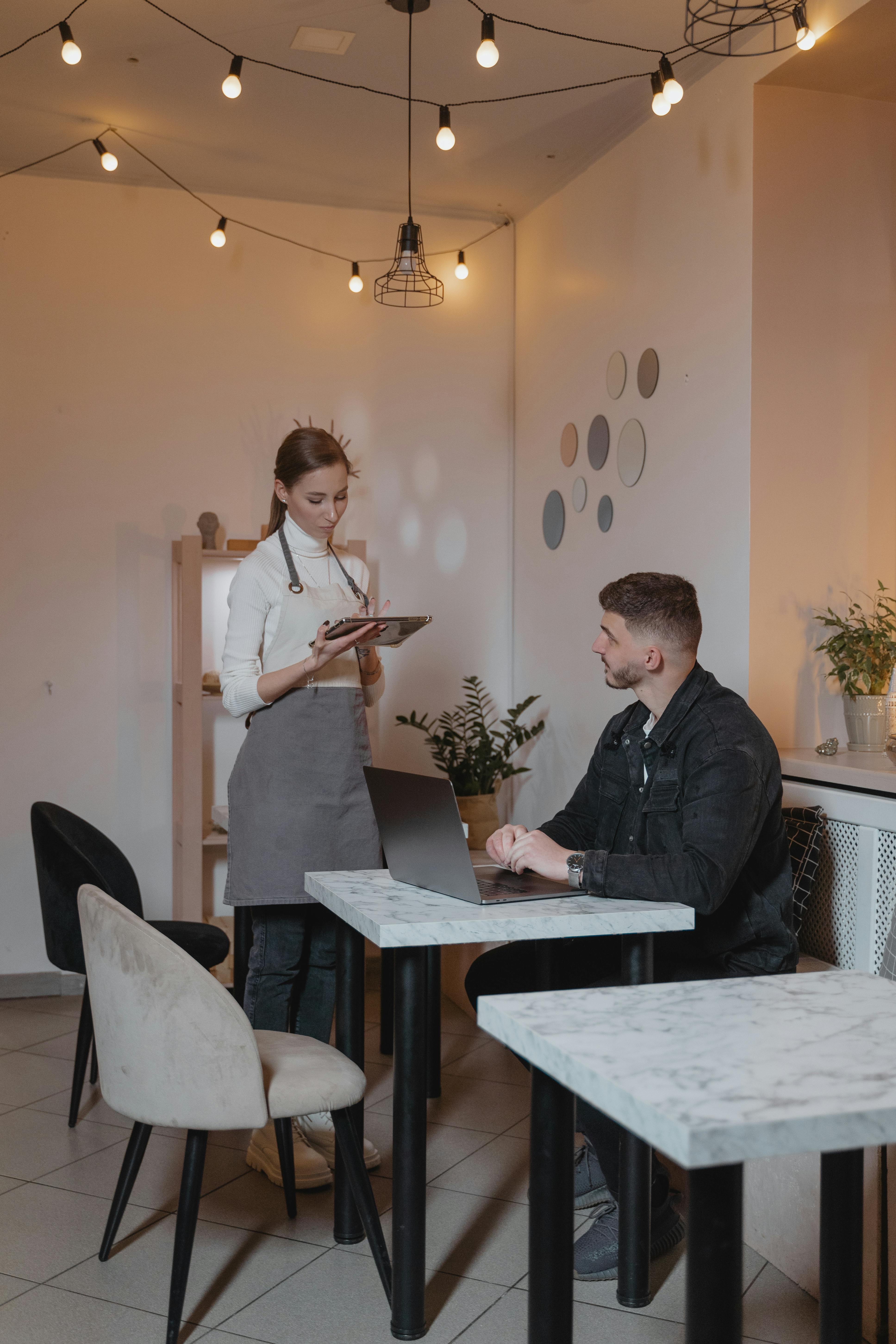 Serveuse discutant avec un client dans un restaurant | Source : Pexels