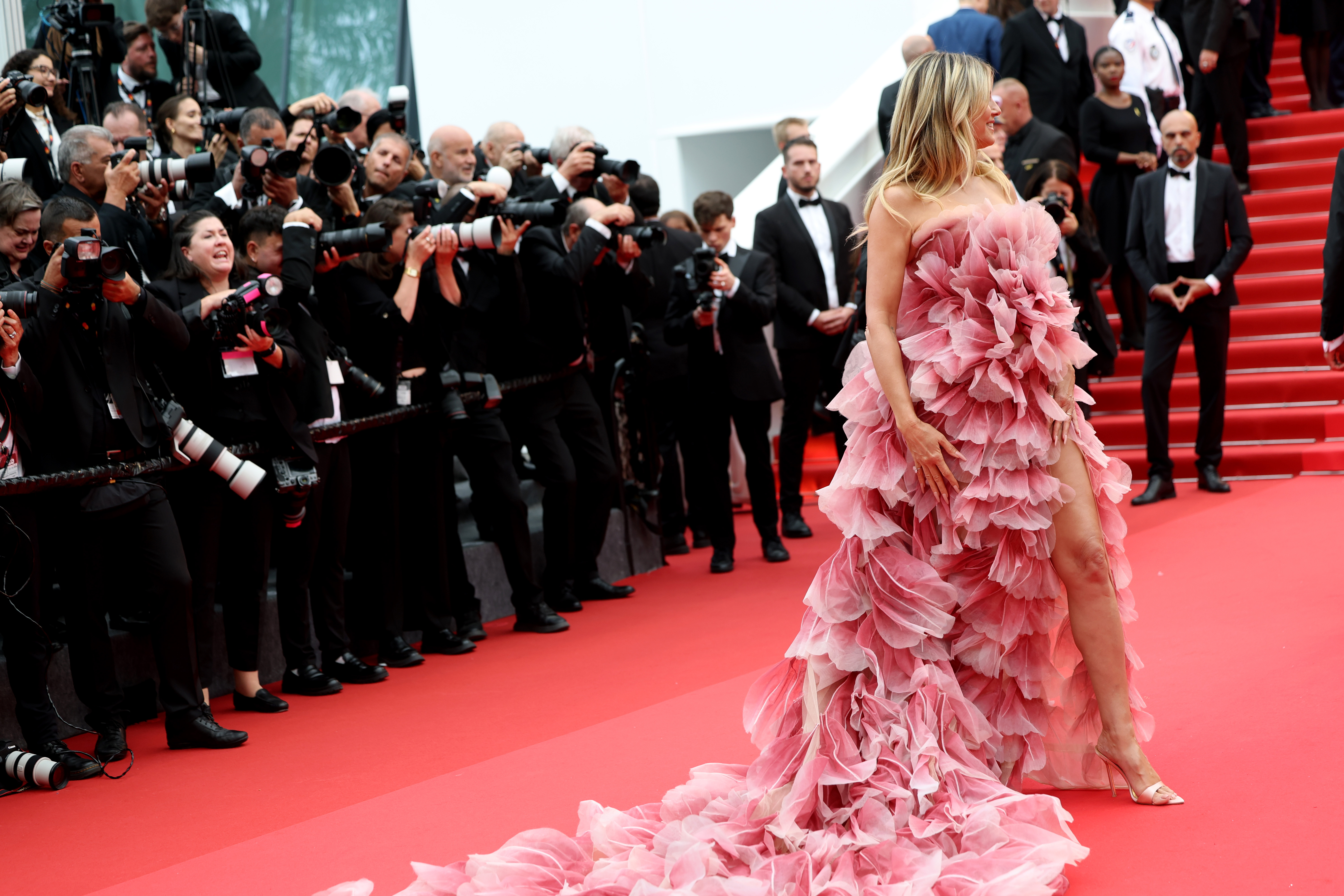 Un plan plus rapproché révèle la beauté complexe de la robe de Heidi Klum - chaque couche de volants imite de délicats pétales, qui brillent doucement dans les tons de rose. L'artisanat est exquis et donne à la robe une qualité romantique, presque éthérée de près.