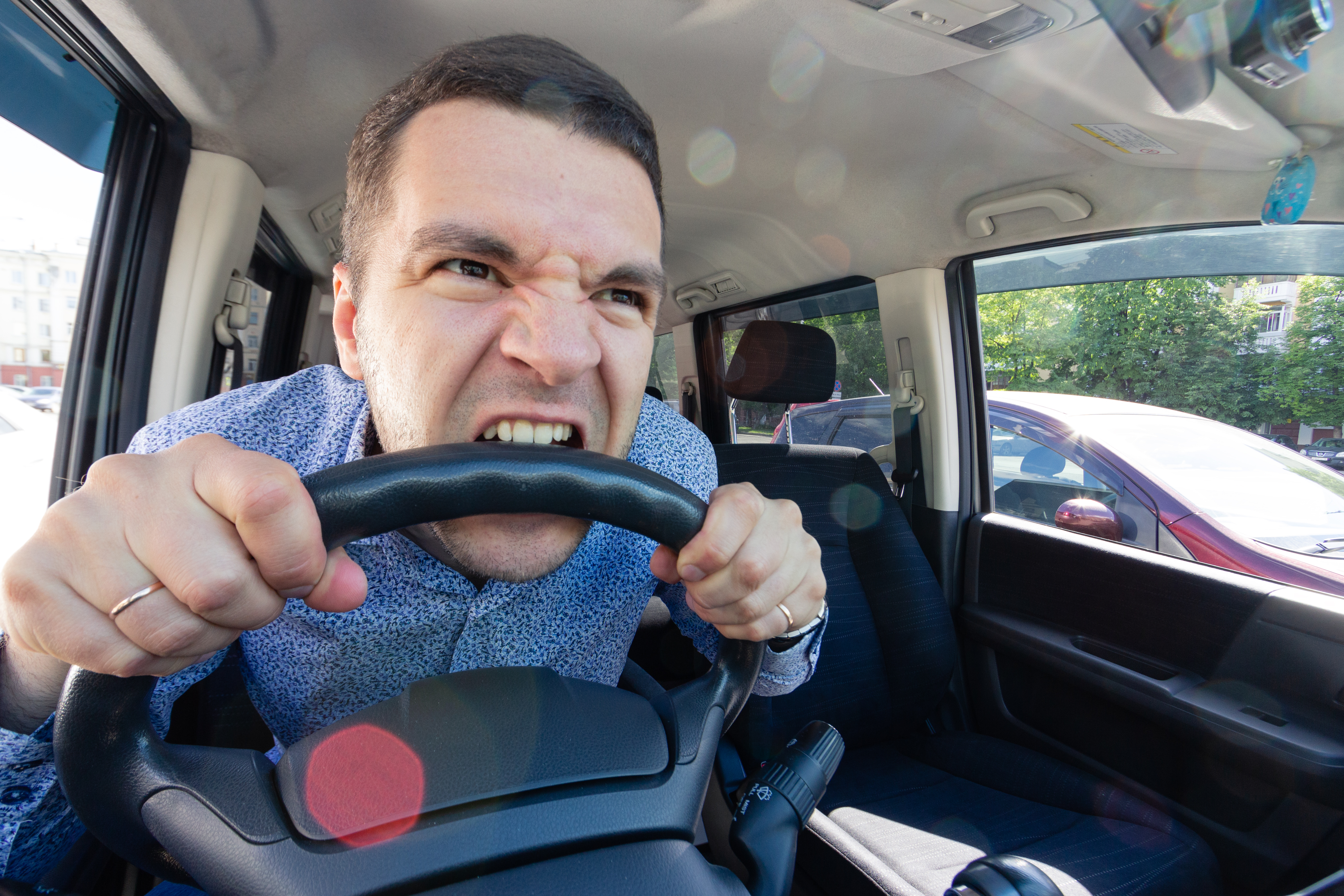 Un jeune homme en colère mord le volant d'une voiture | Source : Shutterstock