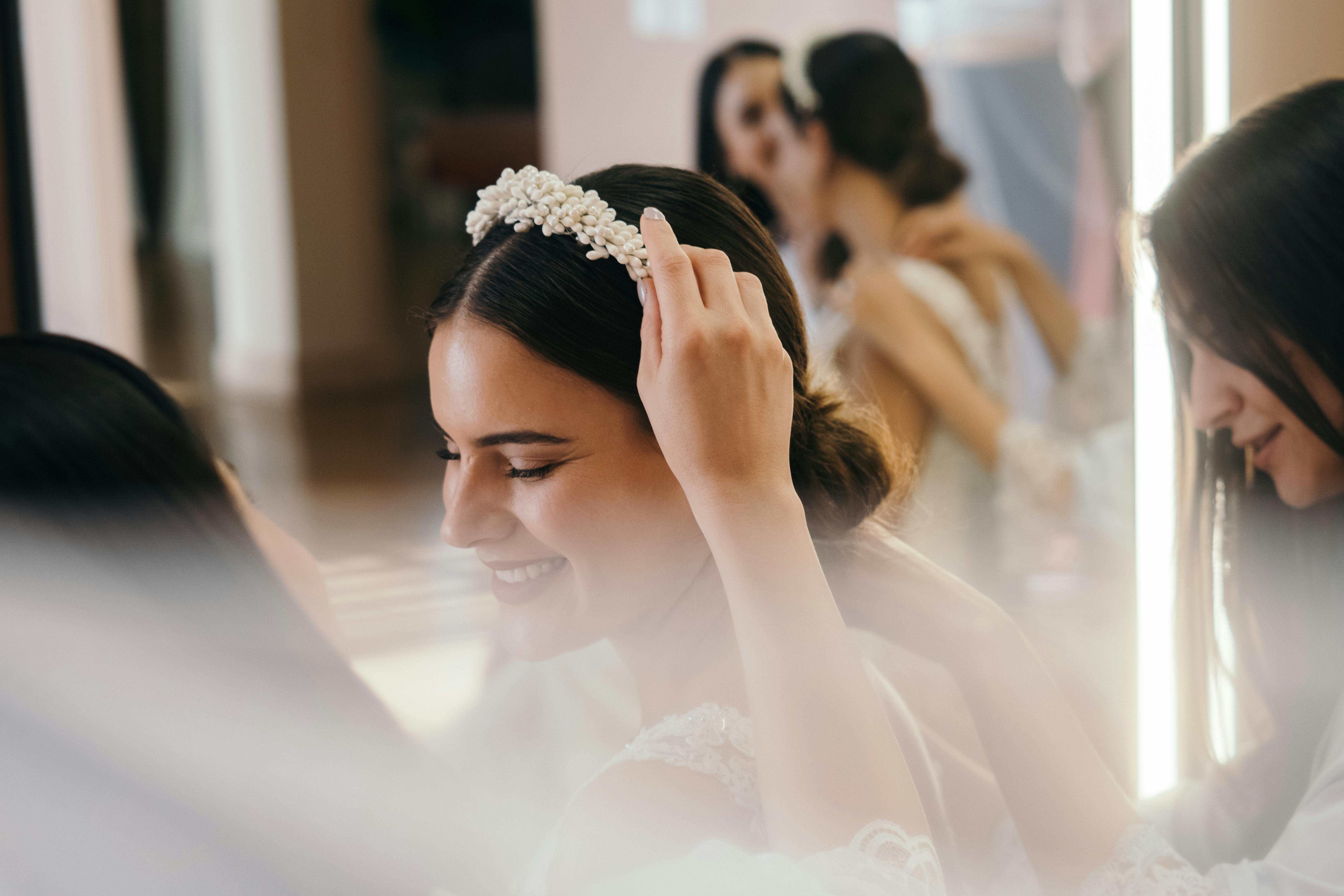 Une demoiselle d'honneur pose un bandeau sur la tête d'une mariée | Source : Pexels