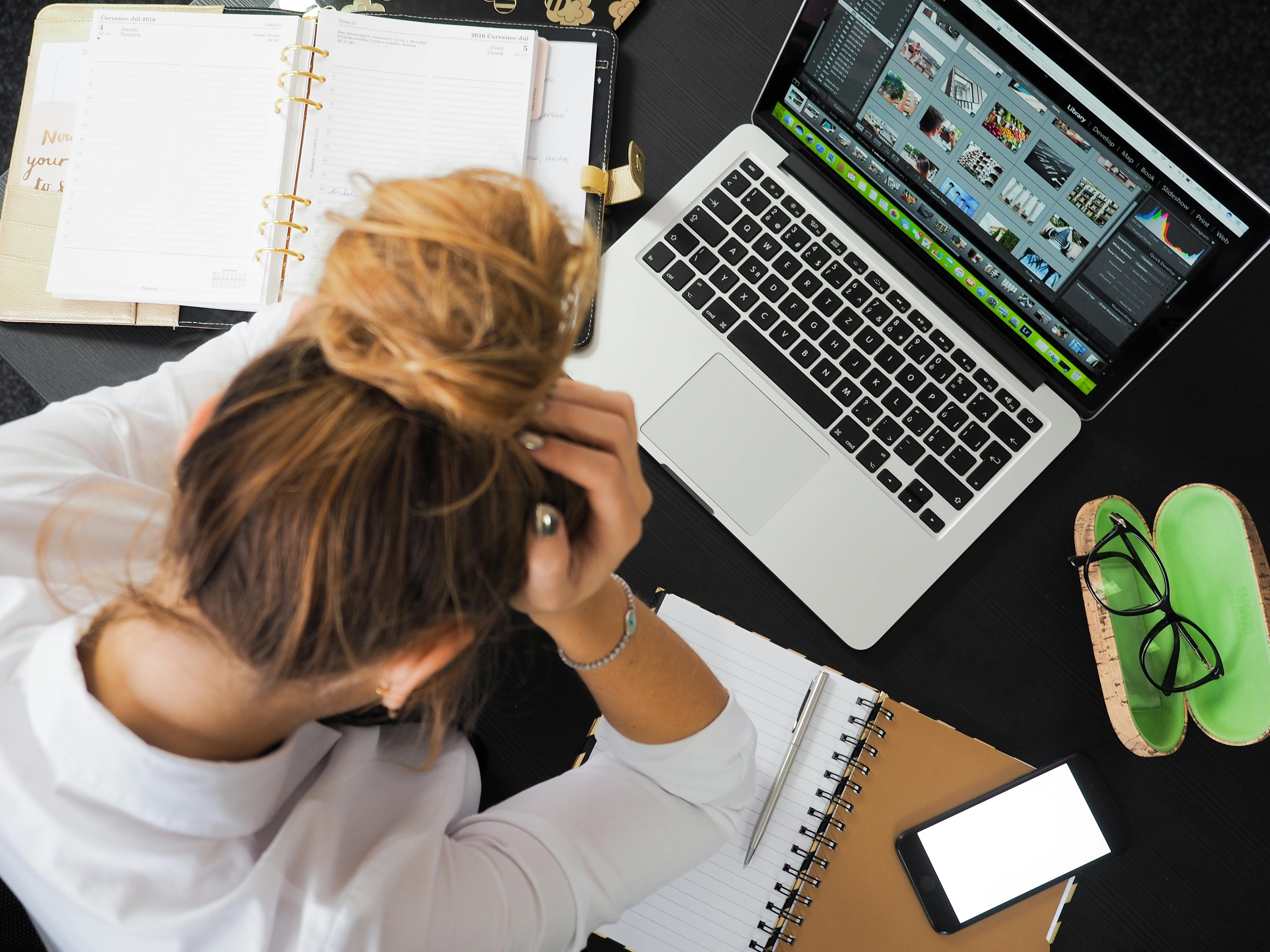 Une jeune femme assise à un bureau avec son agenda et son ordinateur portable | Source : Pexels