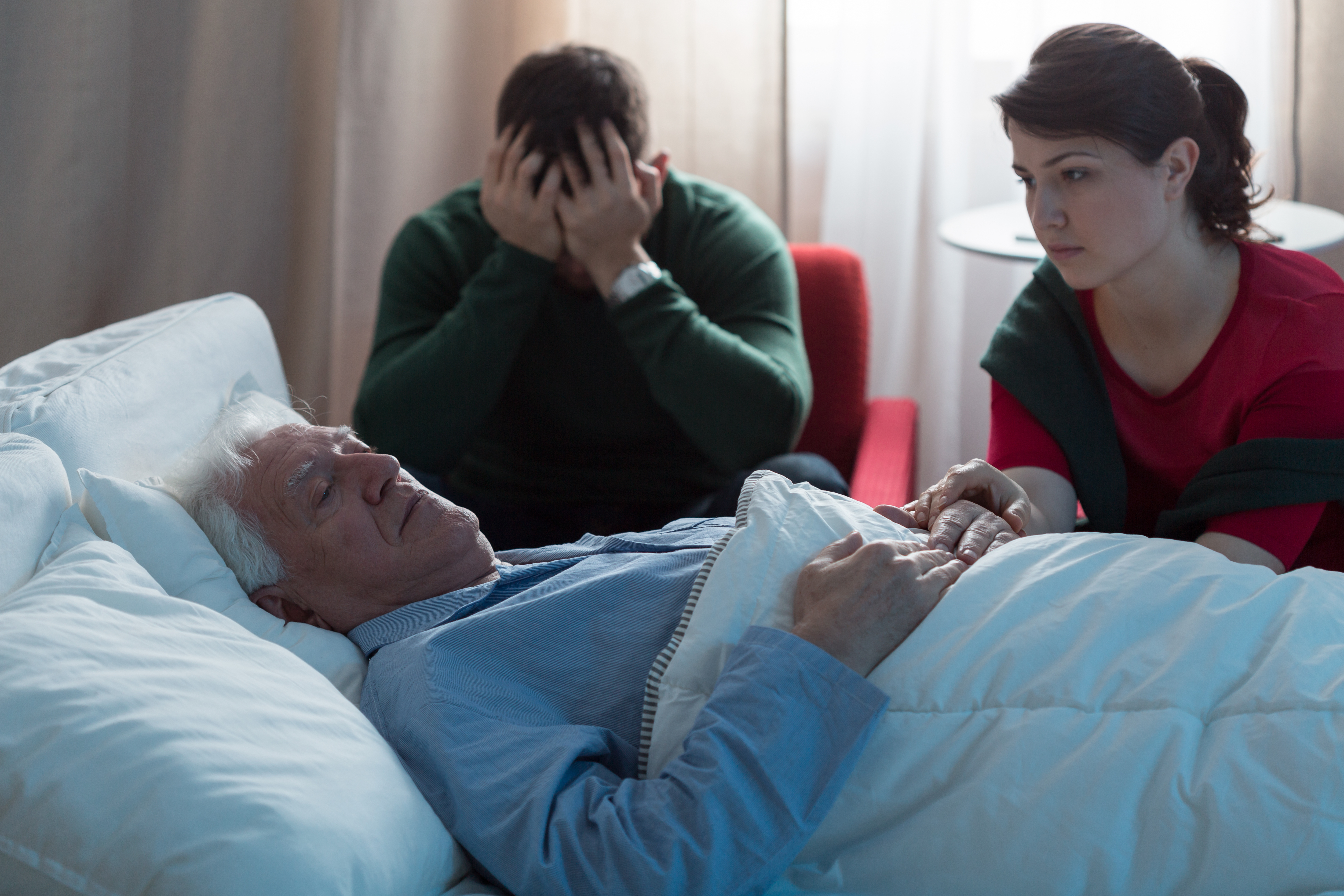 Un vieil homme à l'hôpital entouré de sa famille | Source : Shutterstock