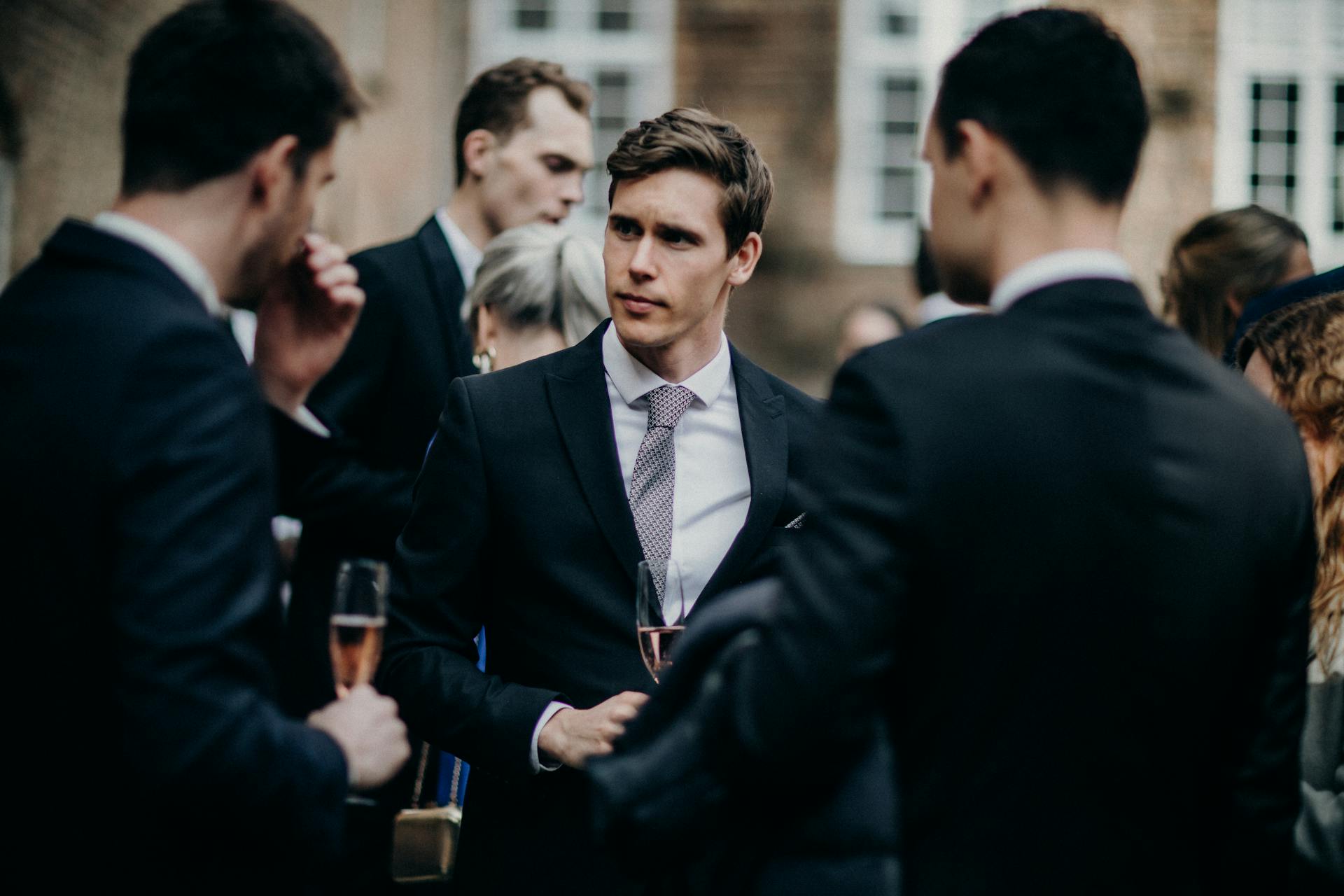 Des hommes en costume discutent lors d'une fête | Source : Pexels